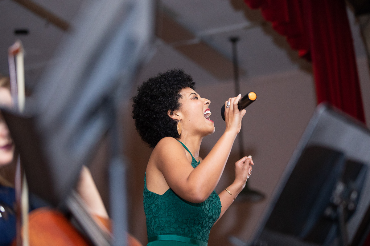 Matron of honor singing at wedding reception variety show in Boston.