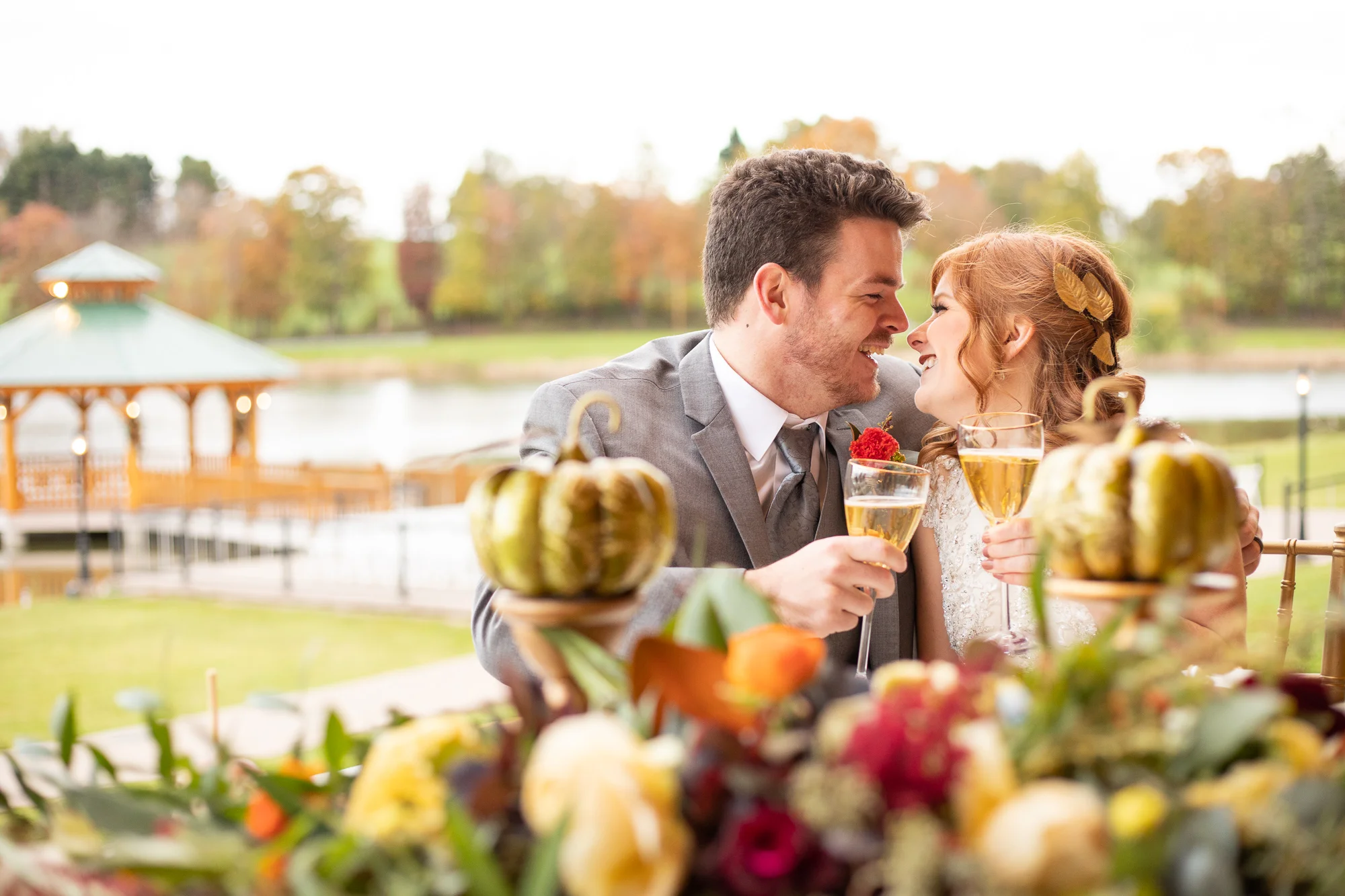 Bride and groom at sweetheart table at autumn styled shoot. The Gathering Place. Events 143. Wood & Grace. Chelsea Party Center. Cable Creations. Bridal Elegance. Ashley’s Mobile Studio. Posies by Patti. Morgan Lei Designs. Kimpels Jewelers.