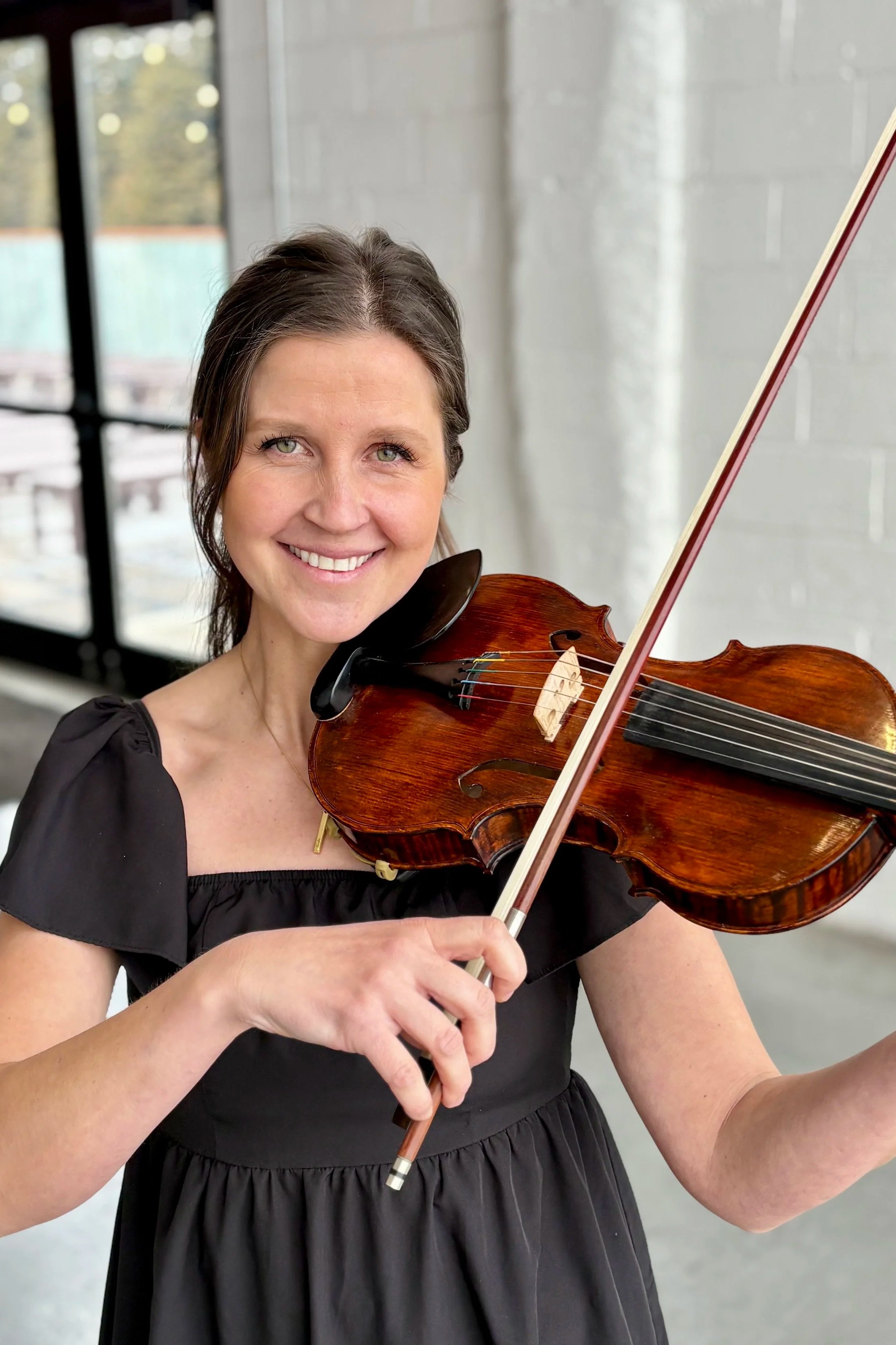 Smiling violinist in black dress at Mojave East wedding venue in Cincinnati
