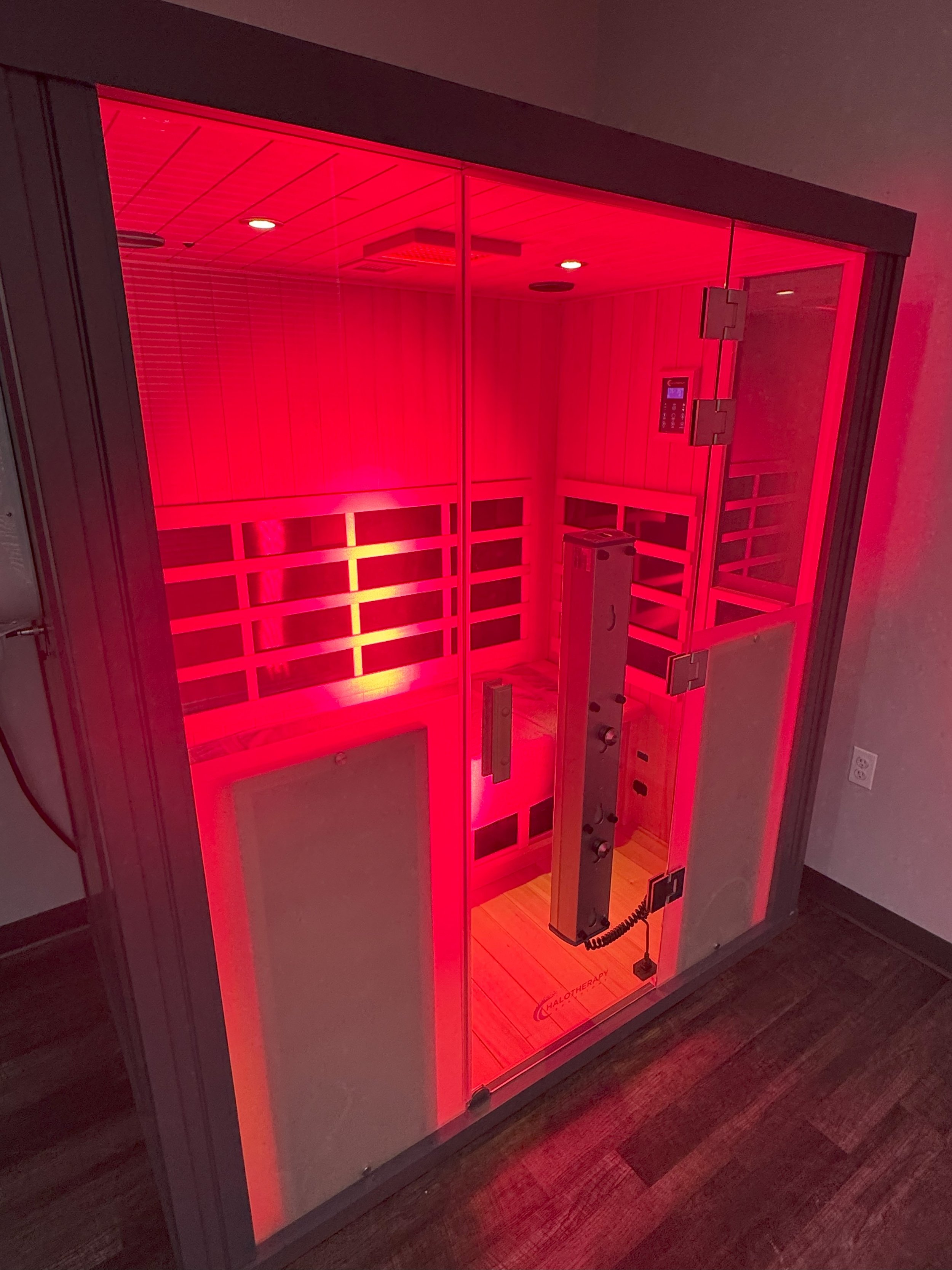 A red-toned infrared sauna with glass doors and interior wooden benches.