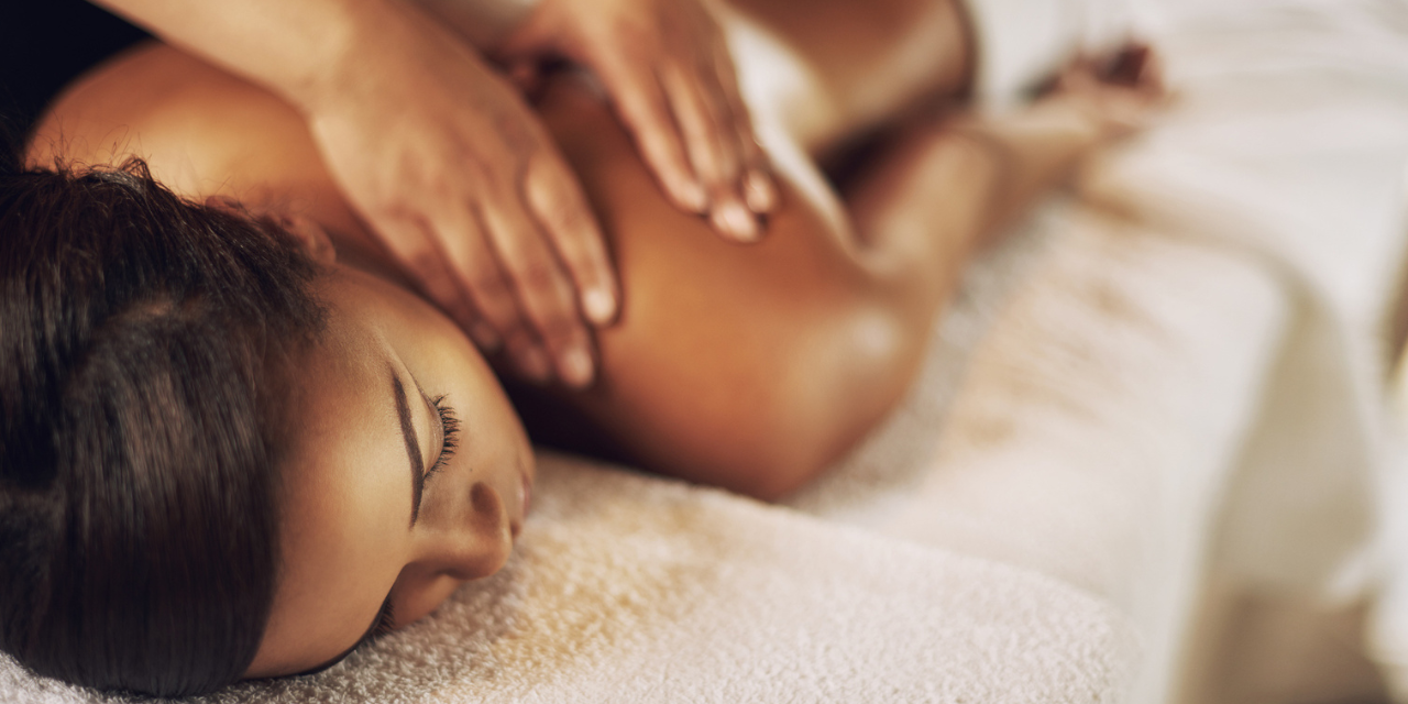 A woman lying down on a biomatwith her eyes closed, resting with her hand on her chest.