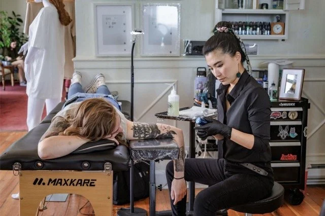Tattoo artist working on a client's arm in a tattoo studio.