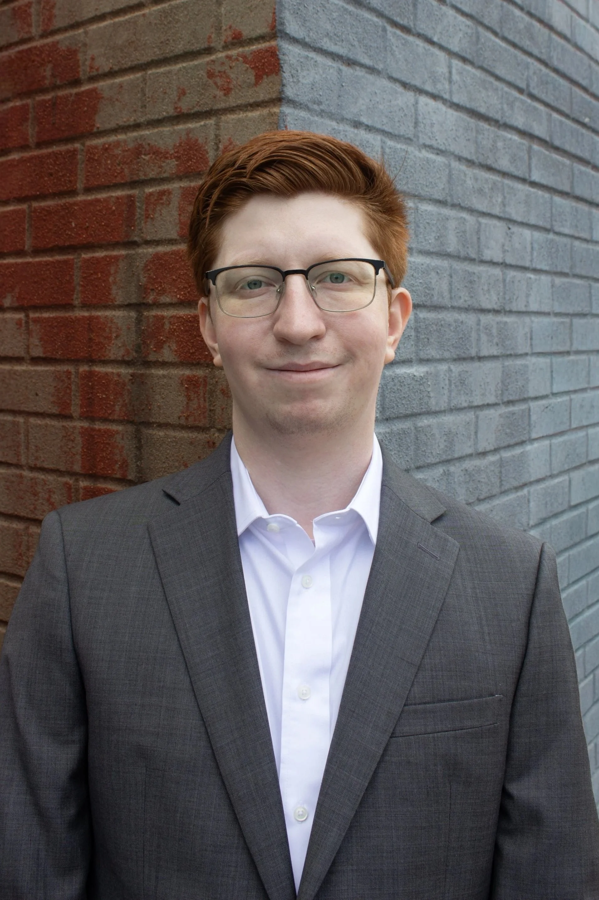 Professional headshot of Ian Berman against a multi-colored brick background.