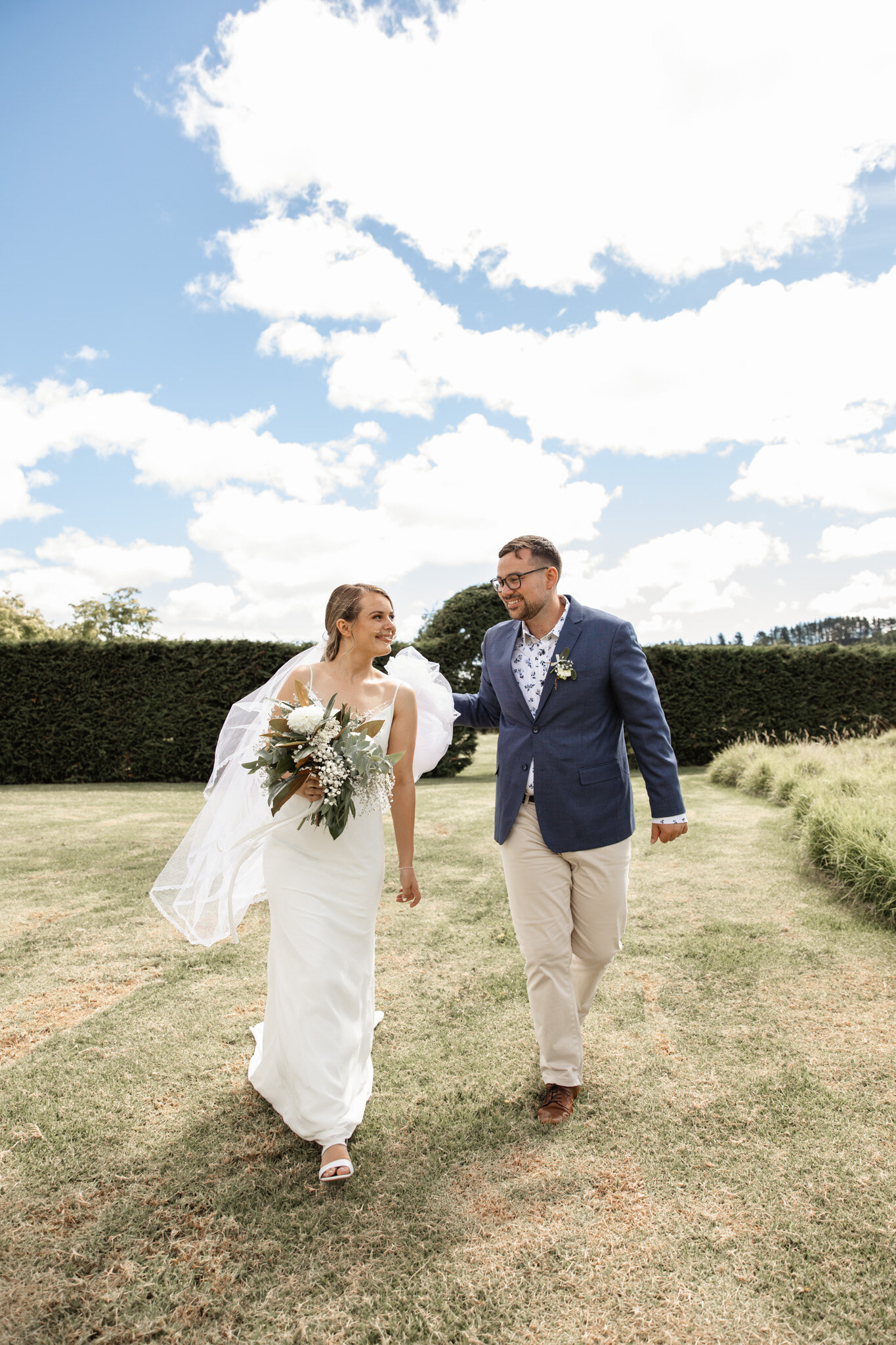 A newly married pair walking hand in hand on a lawn