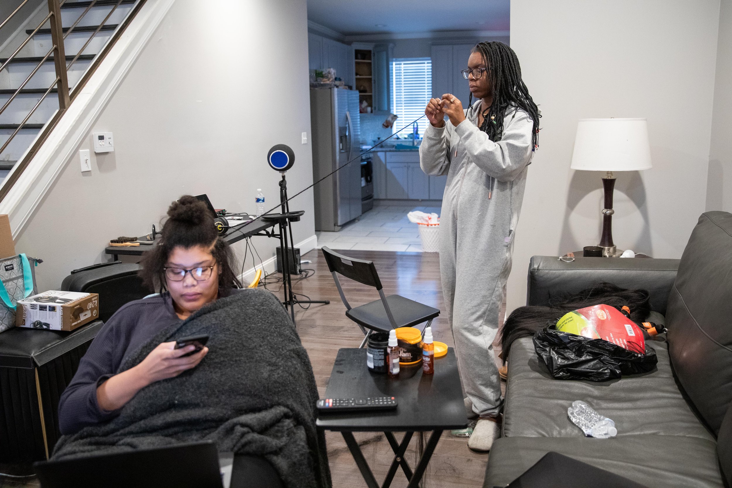   Miarei Harris, owner of BraidsByMi, braids hair extensions for her client at her home in North Philadelphia on Feb. 11, 2021.  