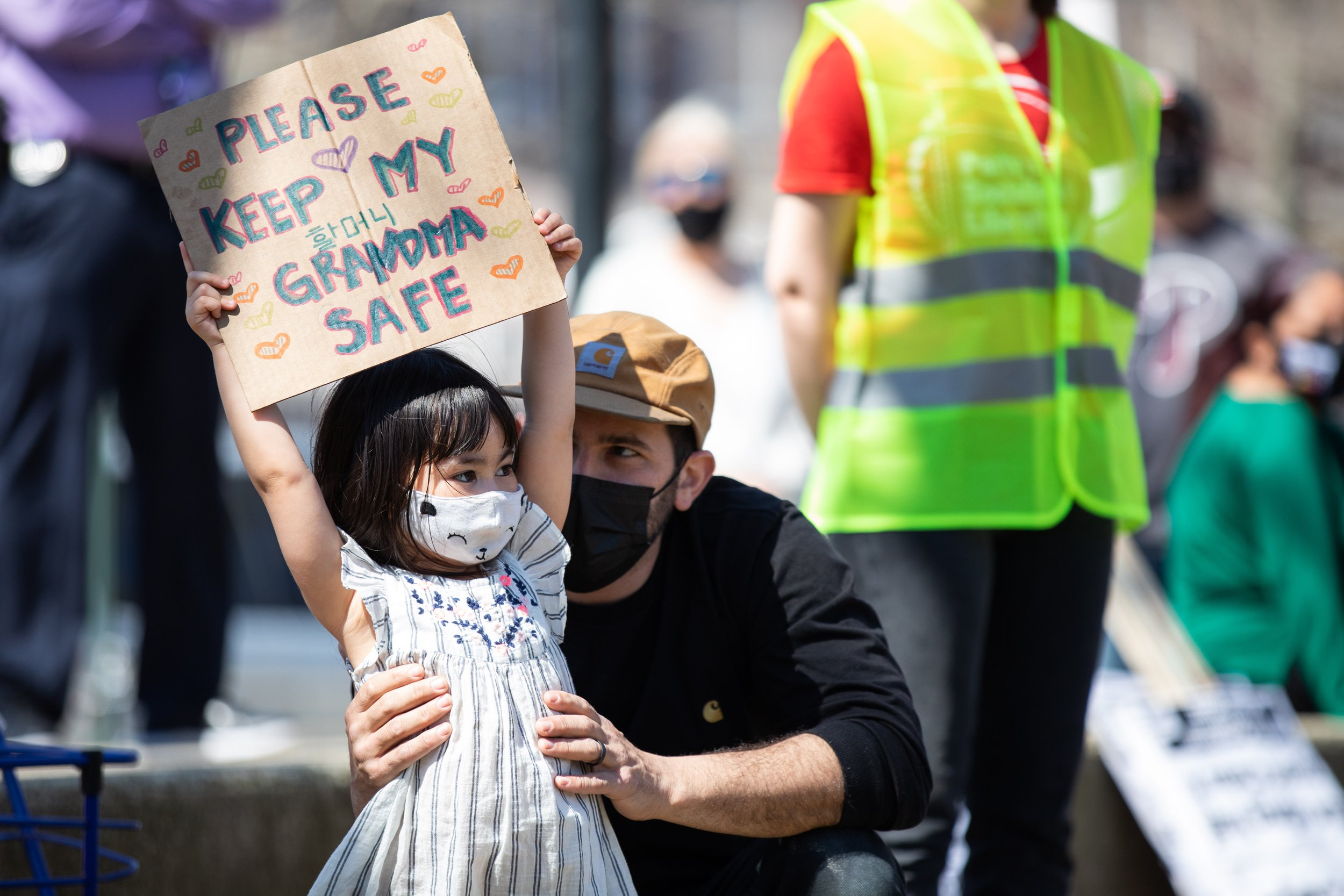   Naomi Klensin (left) stands next to her father, Jacob Klensin, holding a sign that reads “Please keep my grandma safe” at the National Day of Action Against Asian Hate protest at Franklin Square in Philadelphia on March 27, 2021.  