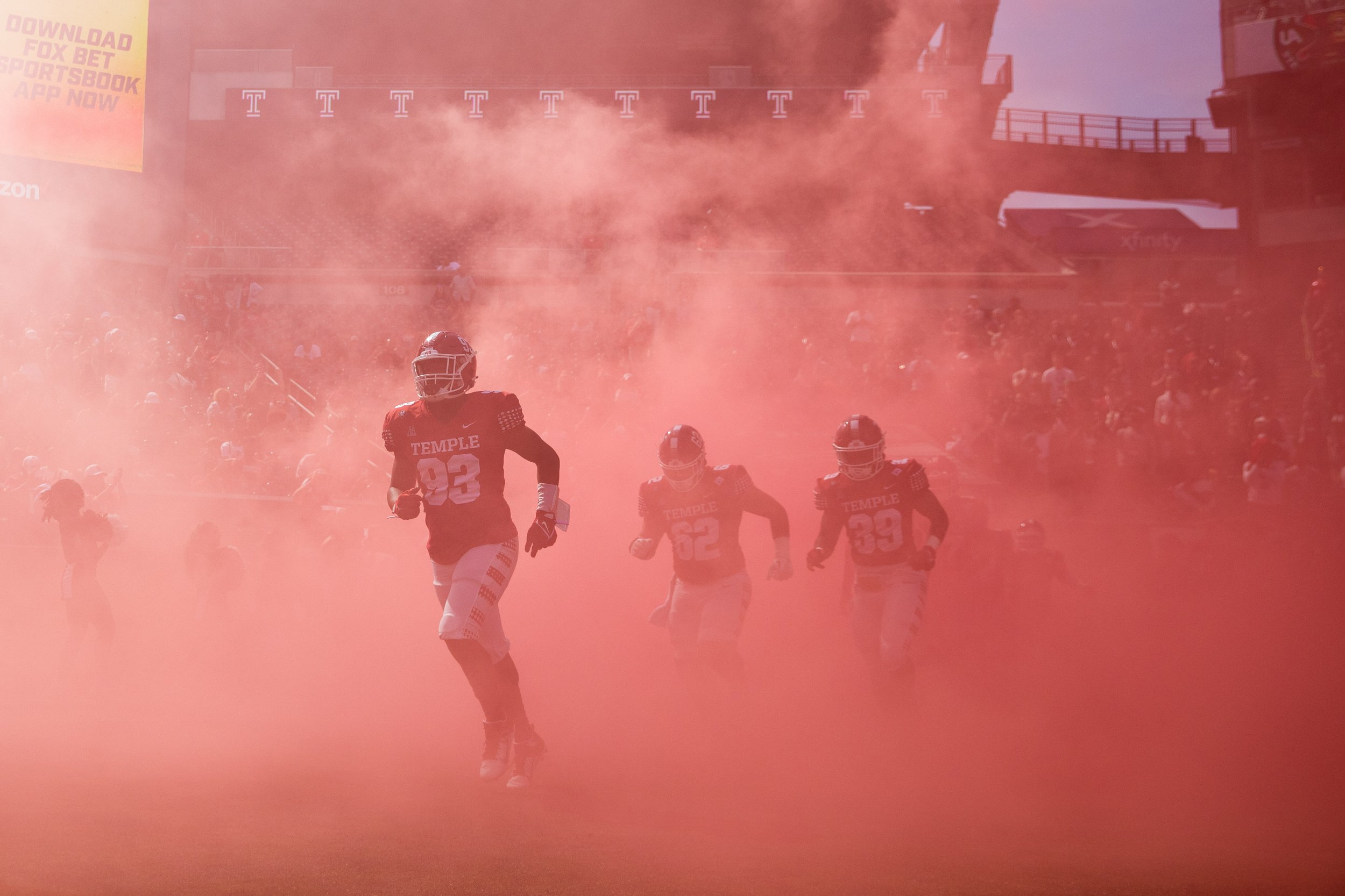   The Temple Owls football team runs out onto the field through red smoke before the start of the homecoming game against the University of Memphis on Oct. 2, 2021.  