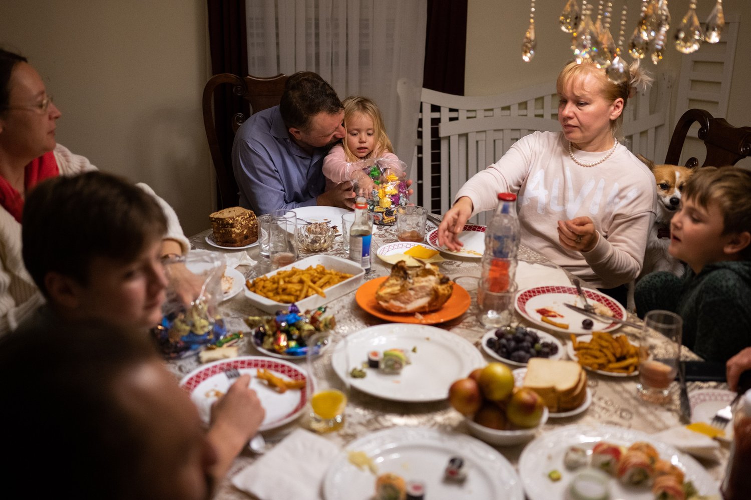   Bishop Luke Zhoba holds Sarra as she holds a bag of Ukrainian candy at the dinner table.  