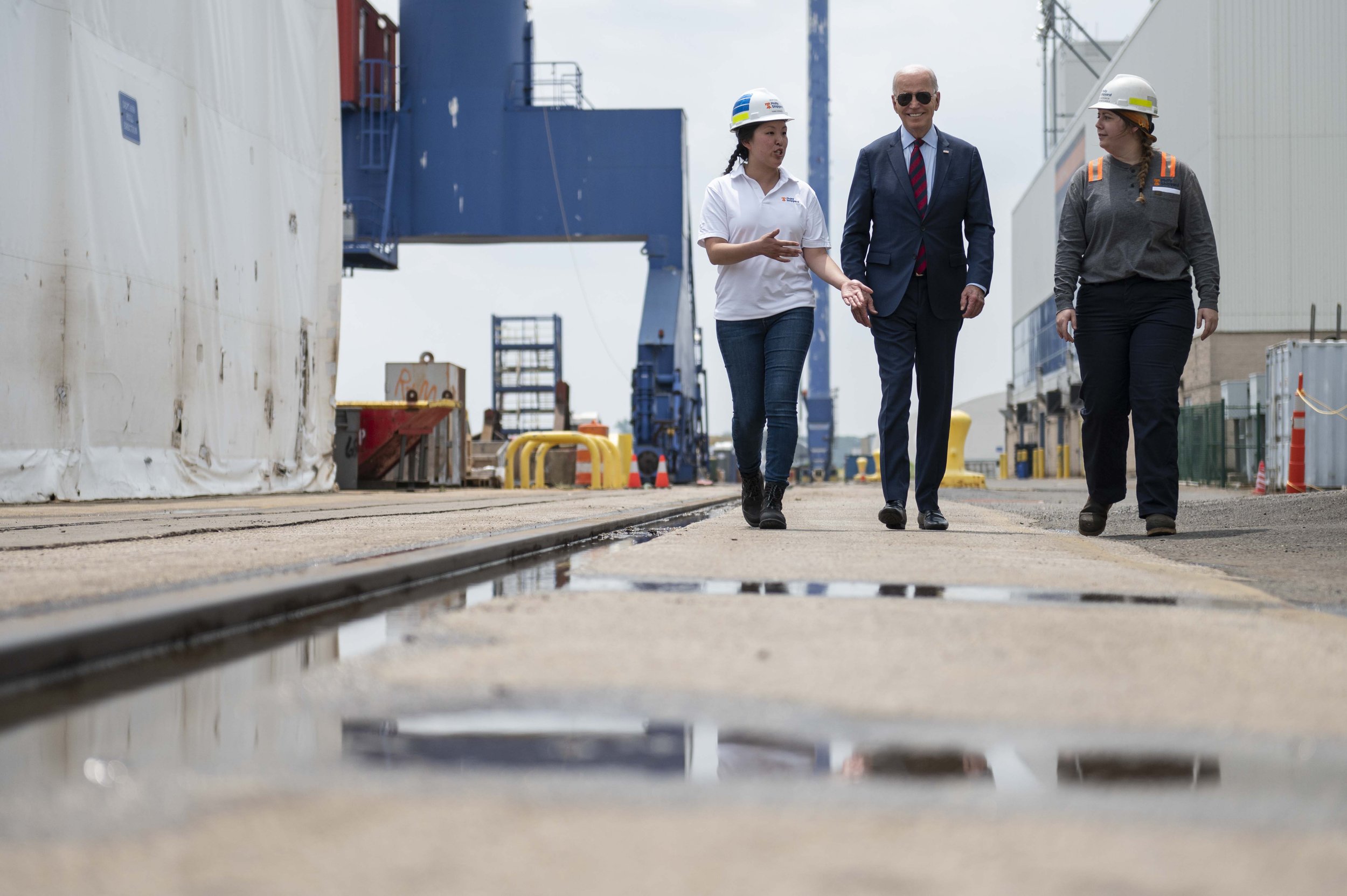   President Biden (center) walks with Philly Ship Yard Apprentice Workers Megan Heileman (left) and Emily Andrewson (right) on Thursday, July 20, 2023.  