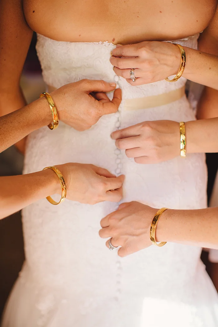 Lovely photo of the bridesmaids helping the bride with her dress