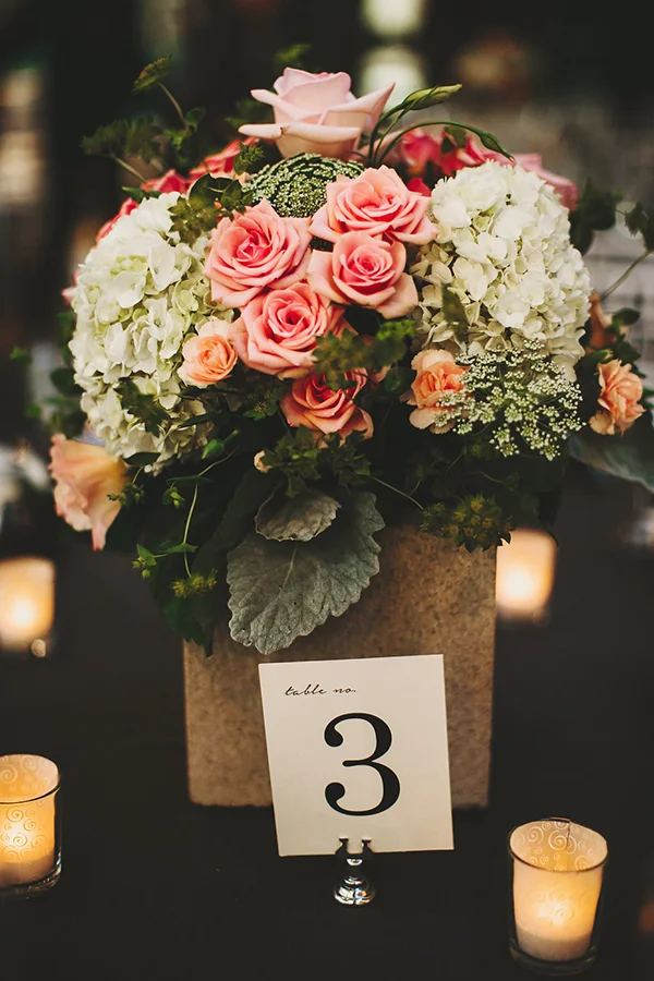 Beautiful wedding reception table centerpiece with pink roses and peach and cream flowers