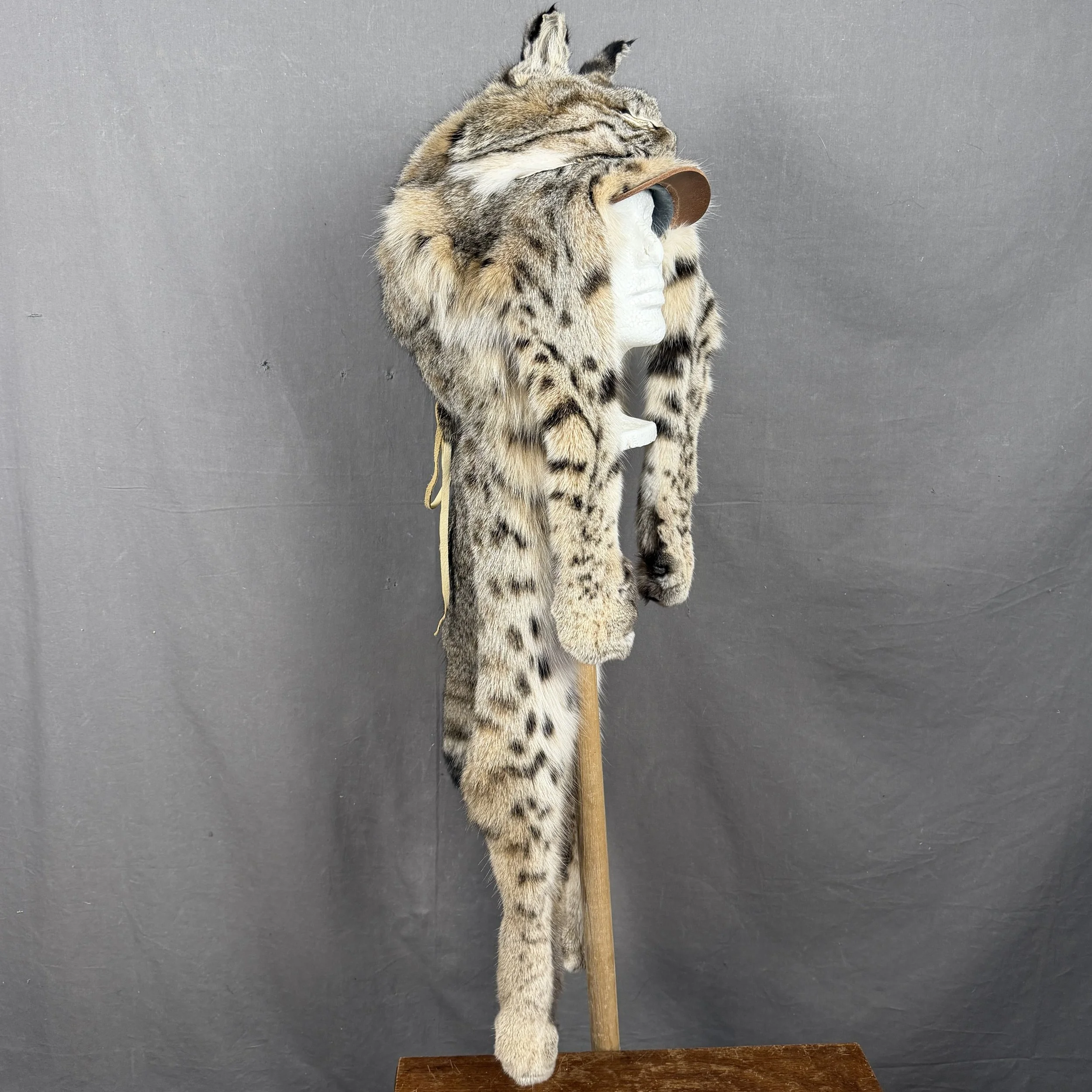 Real Bobcat Mountain Man Fur Hat with Face and Feet. Handcrafted from authentic bobcat fur, this sturdy hat features a detailed bobcat face on the front with sharp eyes and whiskers, plus realistic da
