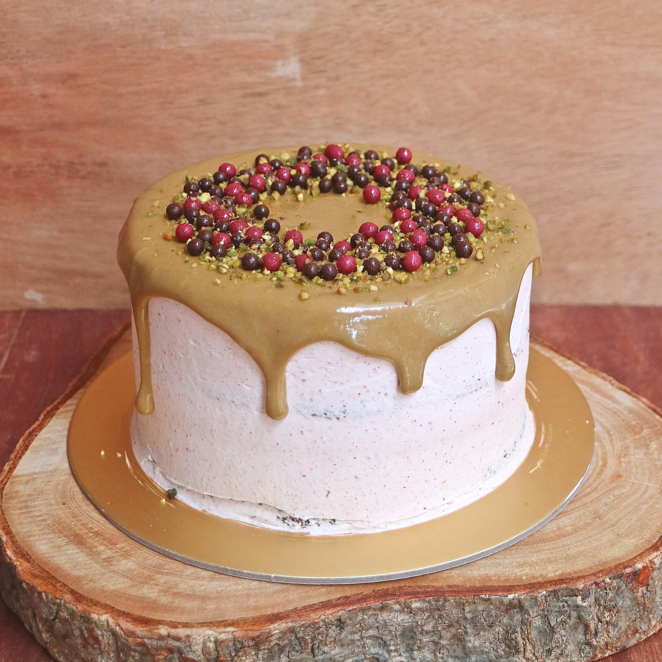 Chocolate Strawberry Pistachio - a 71% single origin dark chocolate sponge filled with homemade strawberry jam, frosted with strawberry buttercream, topped with roasted pistachio glaze and a sprinkof dark chocolate and raspberry chocolate balls. A be