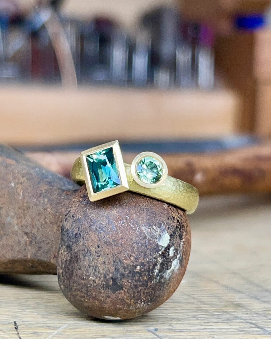 Ring set with lovely pale blue/green sapphire. This stone from Rubyvale has slight silk which only adds to the richness of the colours in this jewel. Recently commissioned in an 18ct gold ring with accompanying bright green sapphire and a hammered te