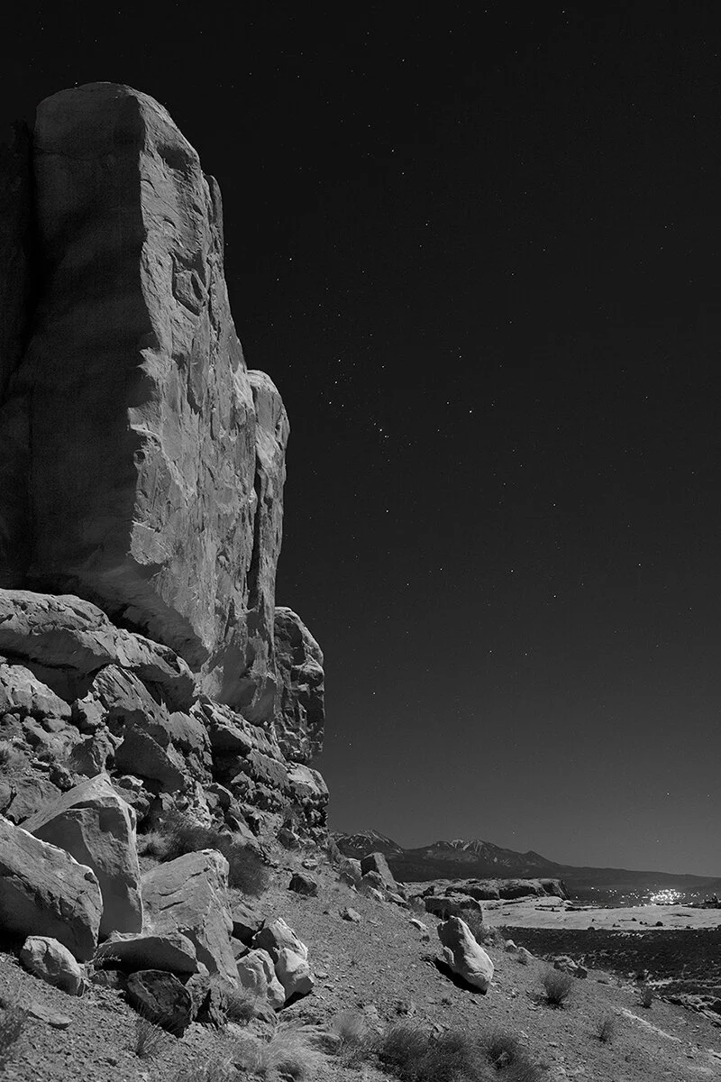   Moonlit formation at Park Avenue, Arches National Park;  La Sal Mountains in the far background, the town of Moab in the lower right distance, and constellation Orion in the sky above (October 2020)  