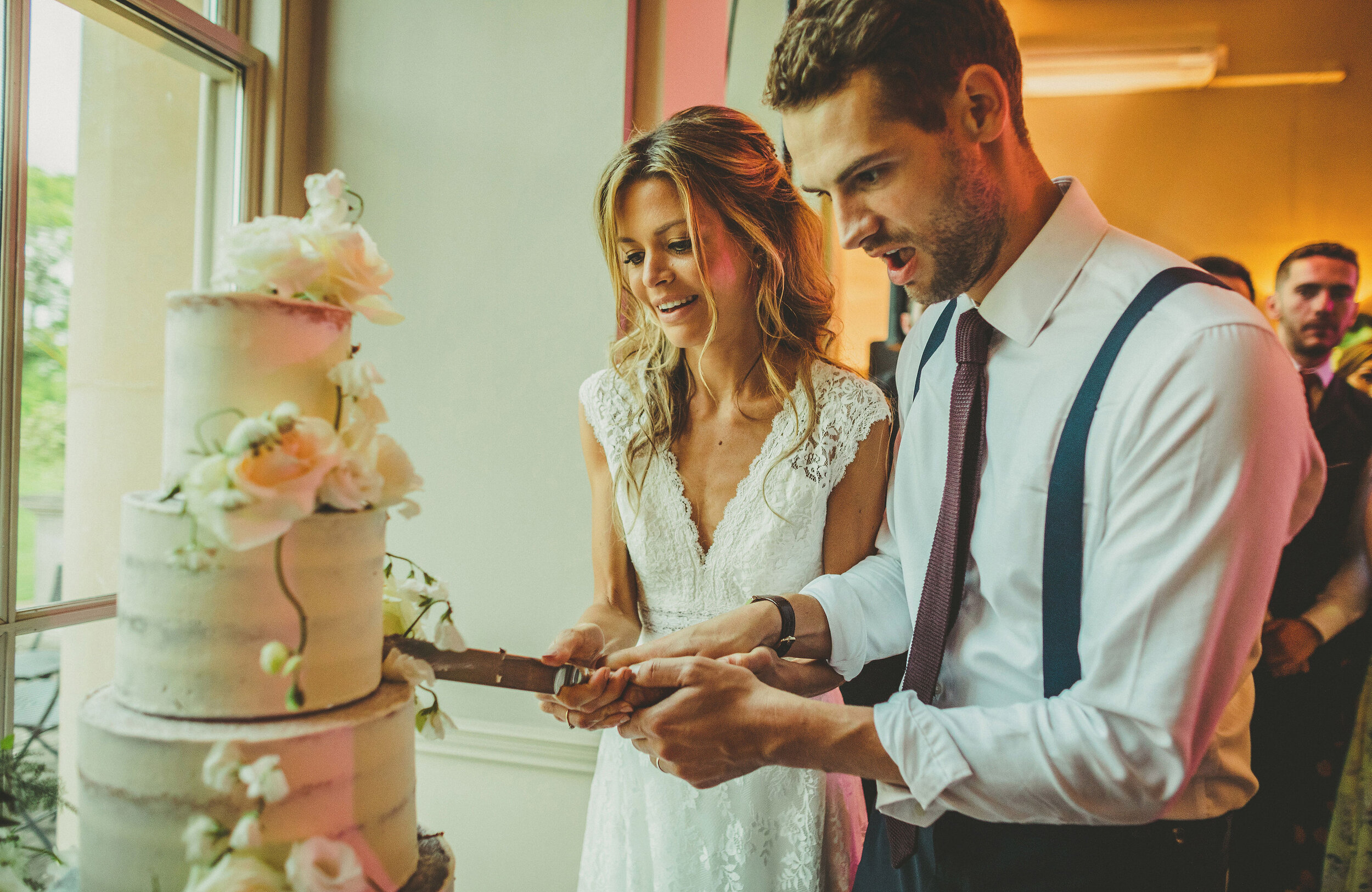  Bride and Groom cutting semi-naked wedding cake by The Confetti Cakery, fresh flowers by All Bunched Up at Stubton Hall, Newark. 