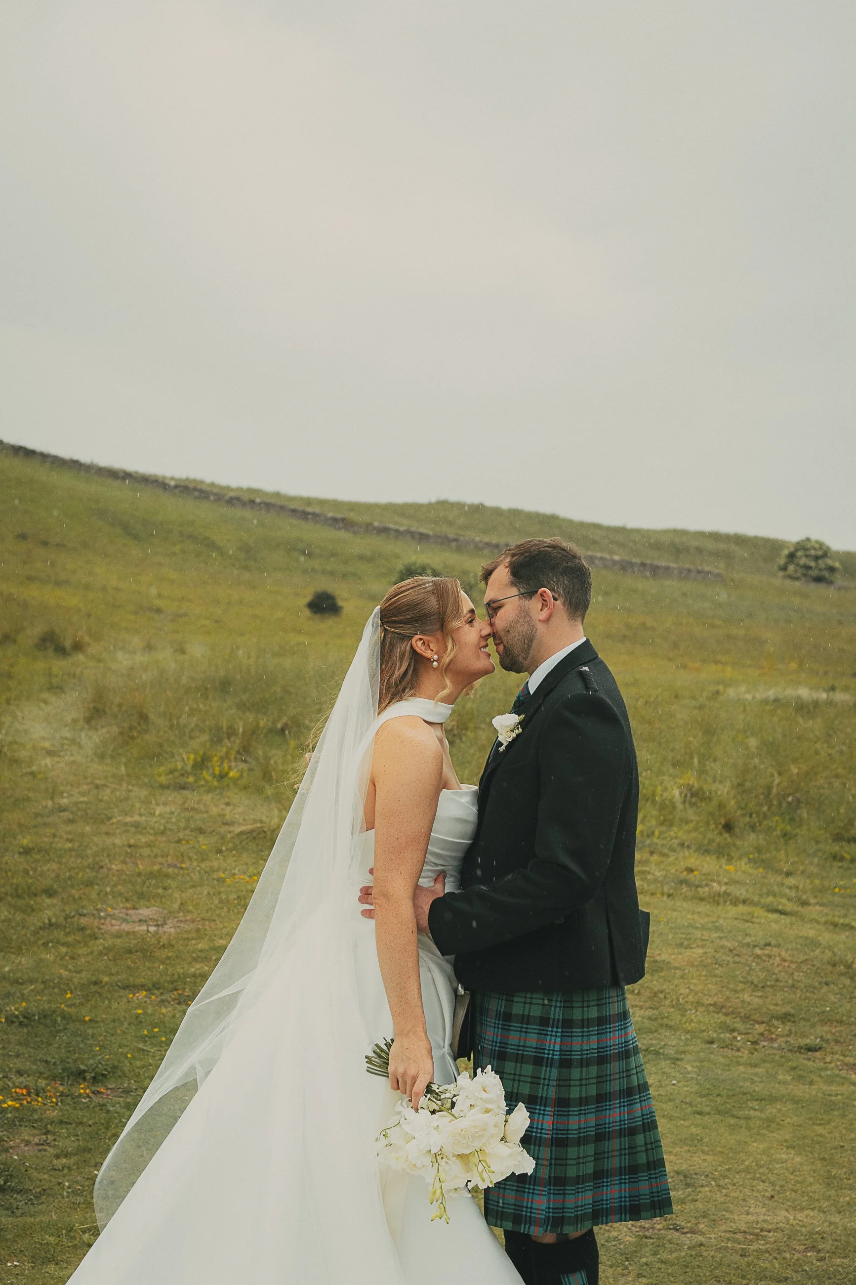 Bride and groom sharing a kiss in the countryside surrounding Broxmouth Courtyard in East Lothian.