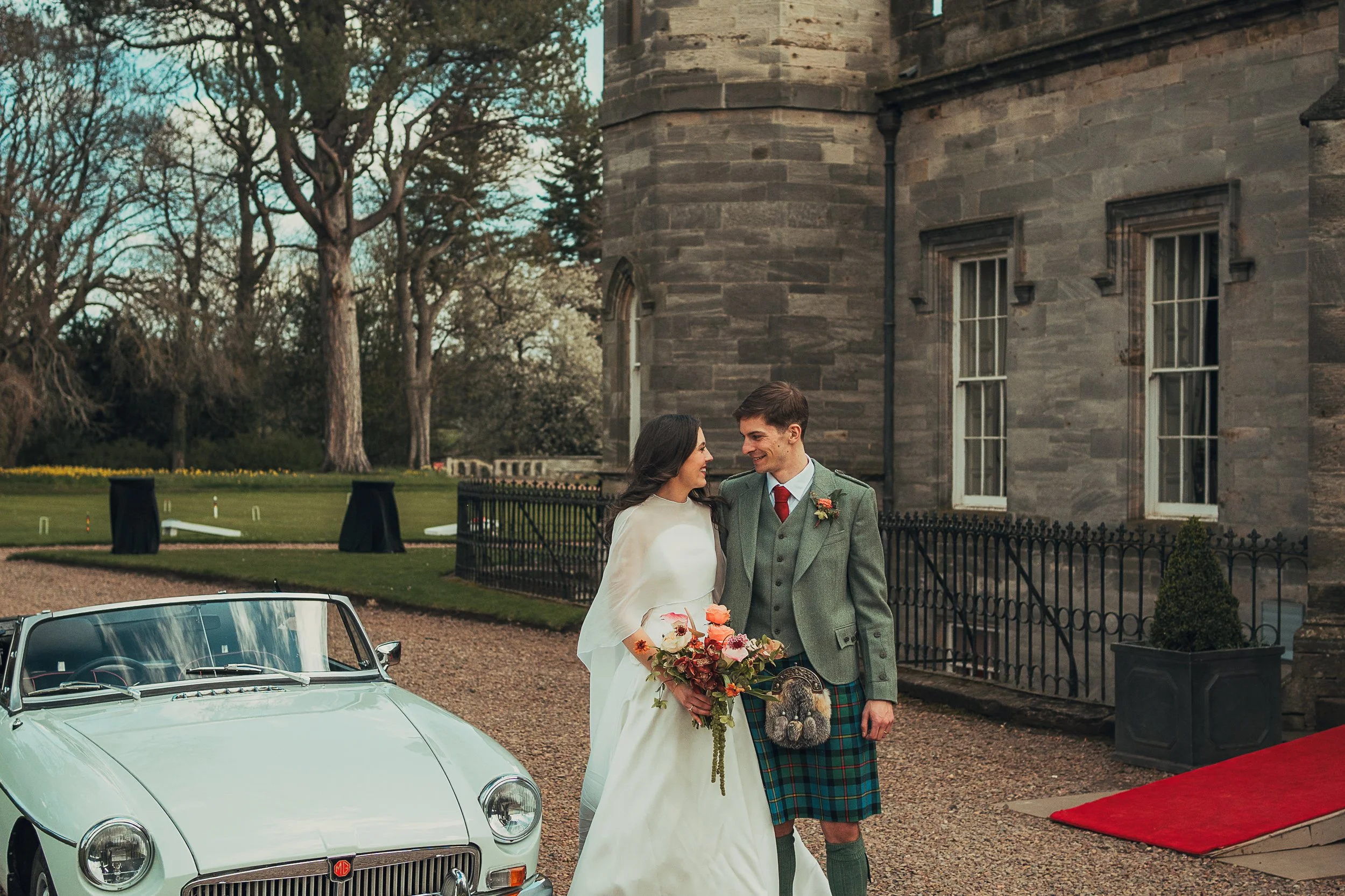 Bride and groom beside a vintage convertible wedding car in Pentcaitland, East Lothian