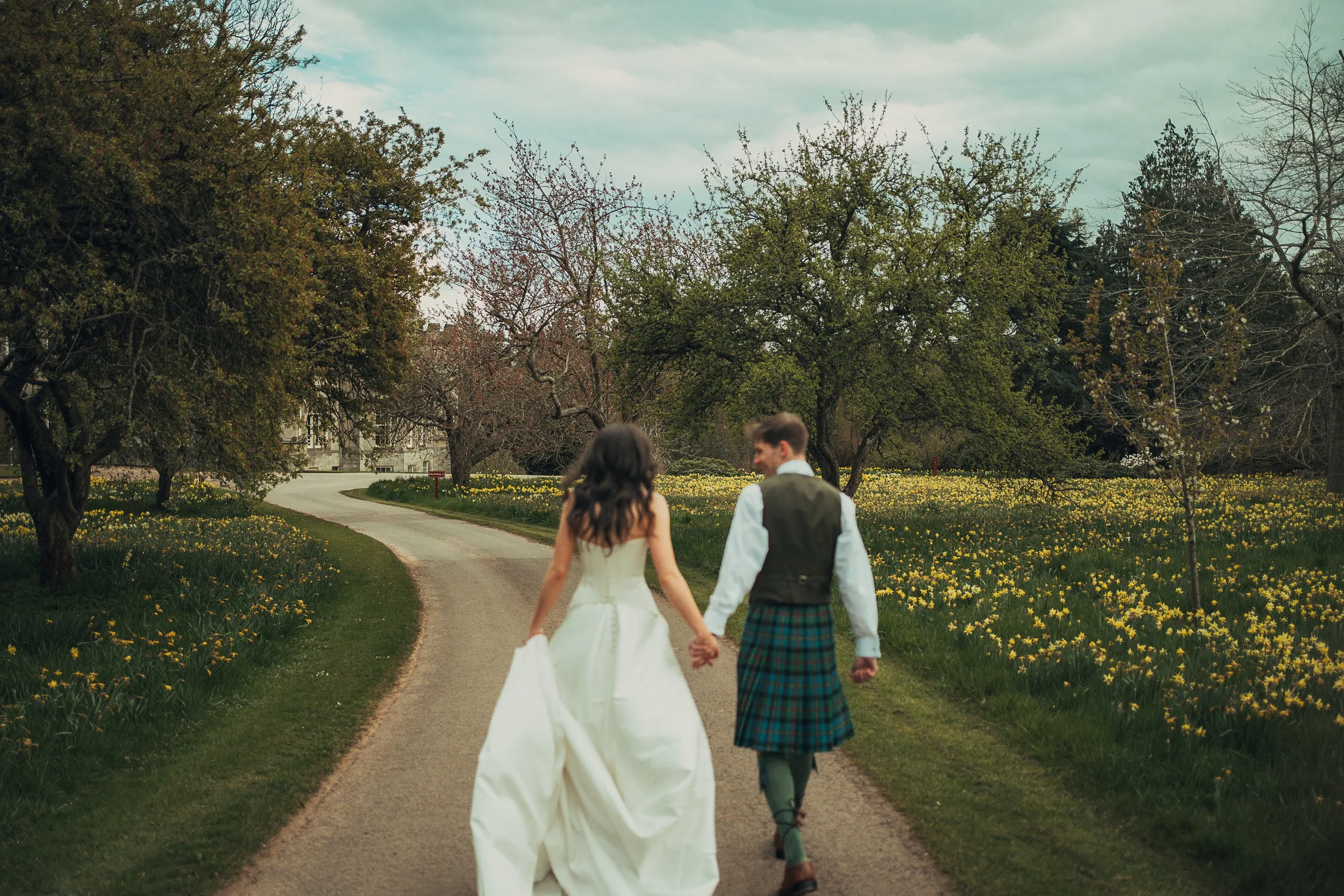 couple-walking-driveway-winton-castle-hand-in-hand.jpg