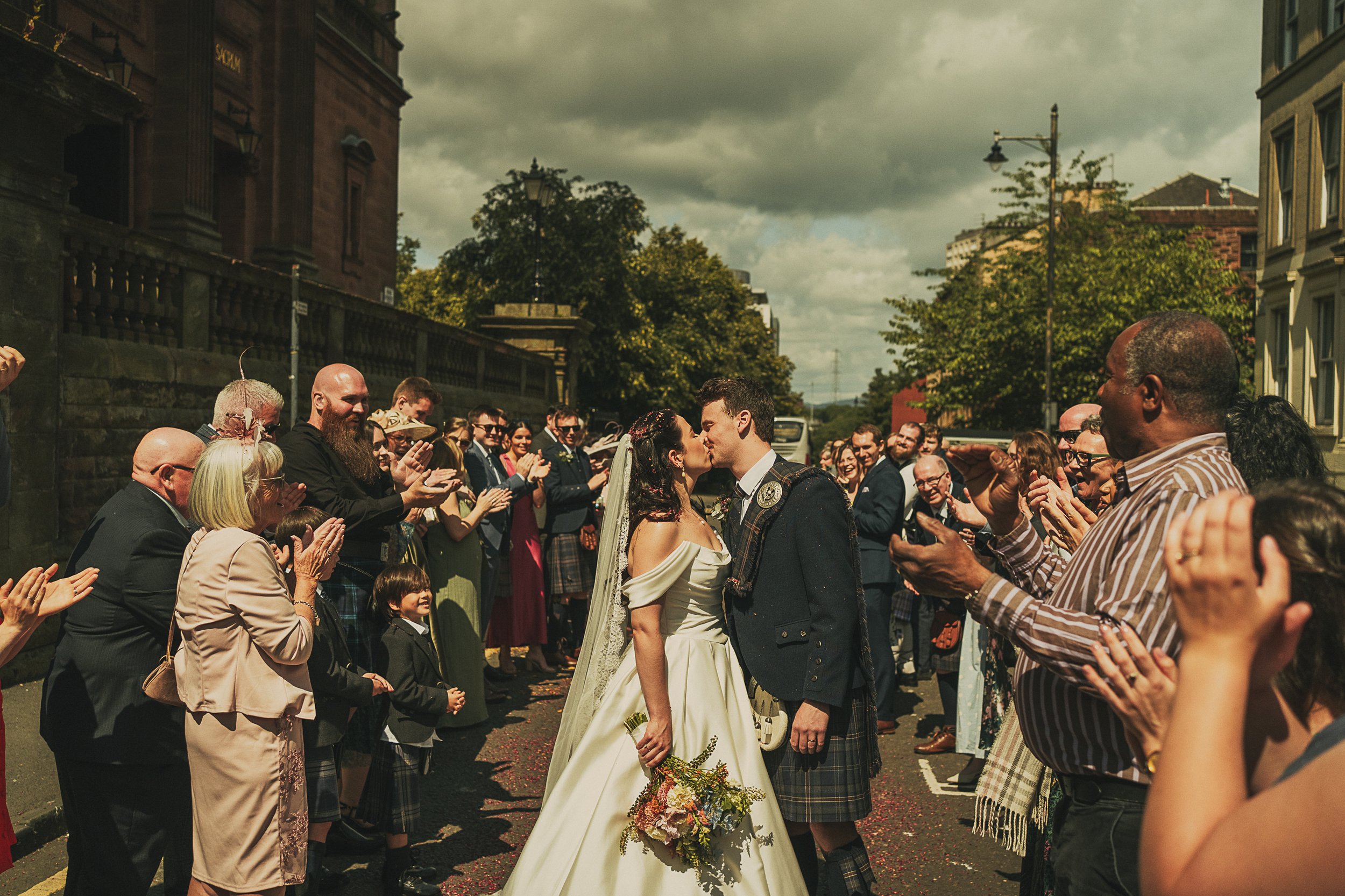 claire-adam-kissing-amongst-wedding-guests-killearn.jpg