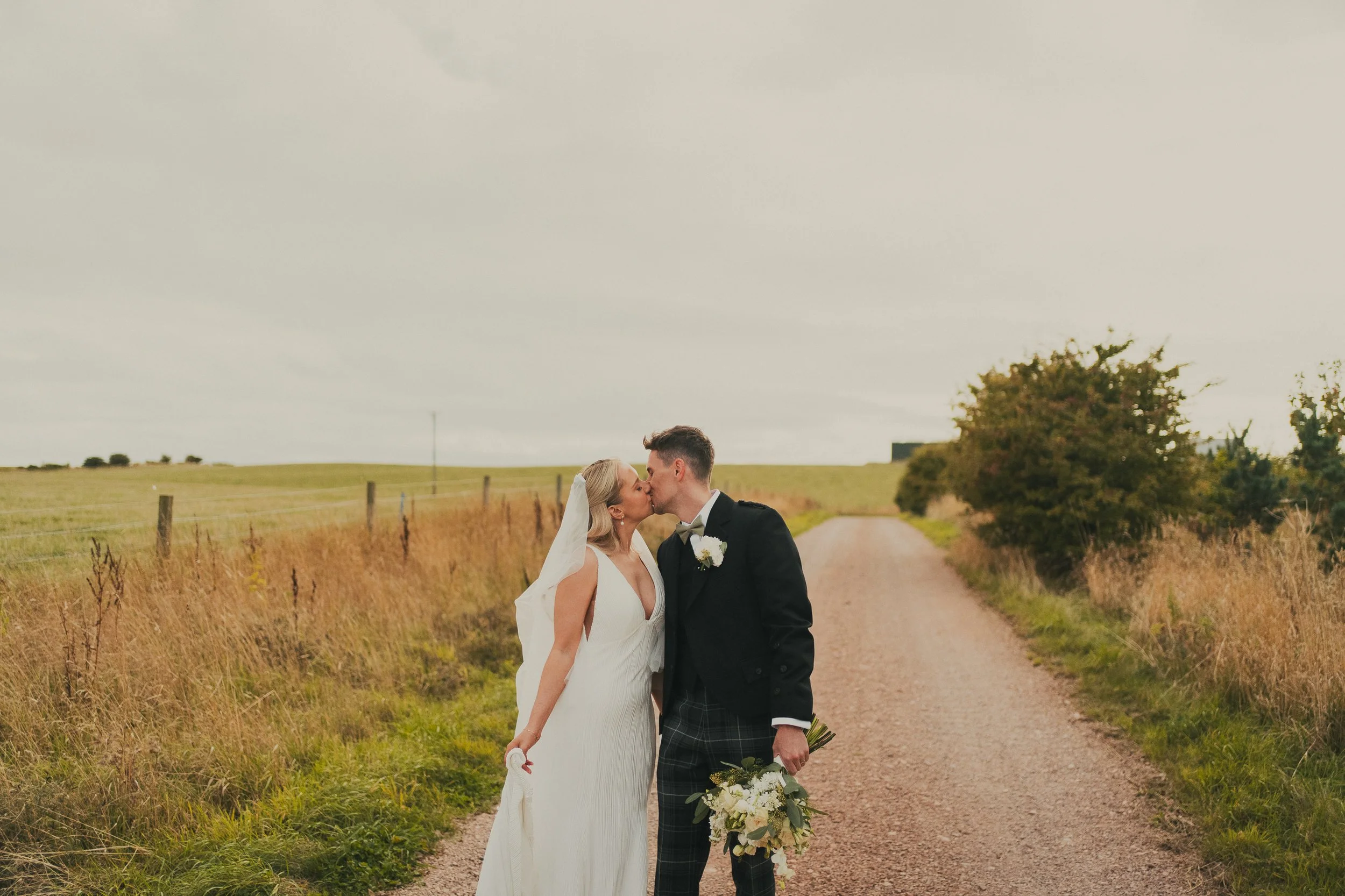 robyn-robbie-falside-mill-wedding-farm-road-kiss.jpg