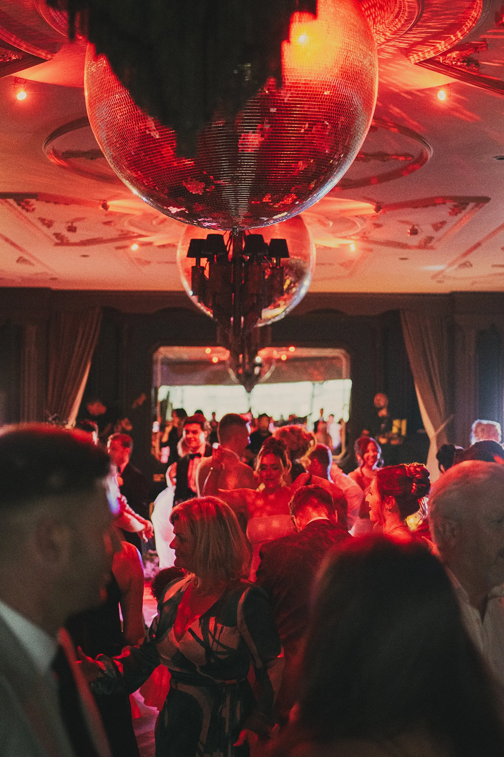 Guests celebrating on the dance floor beneath oversized disco balls at a Cornhill Castle wedding reception.