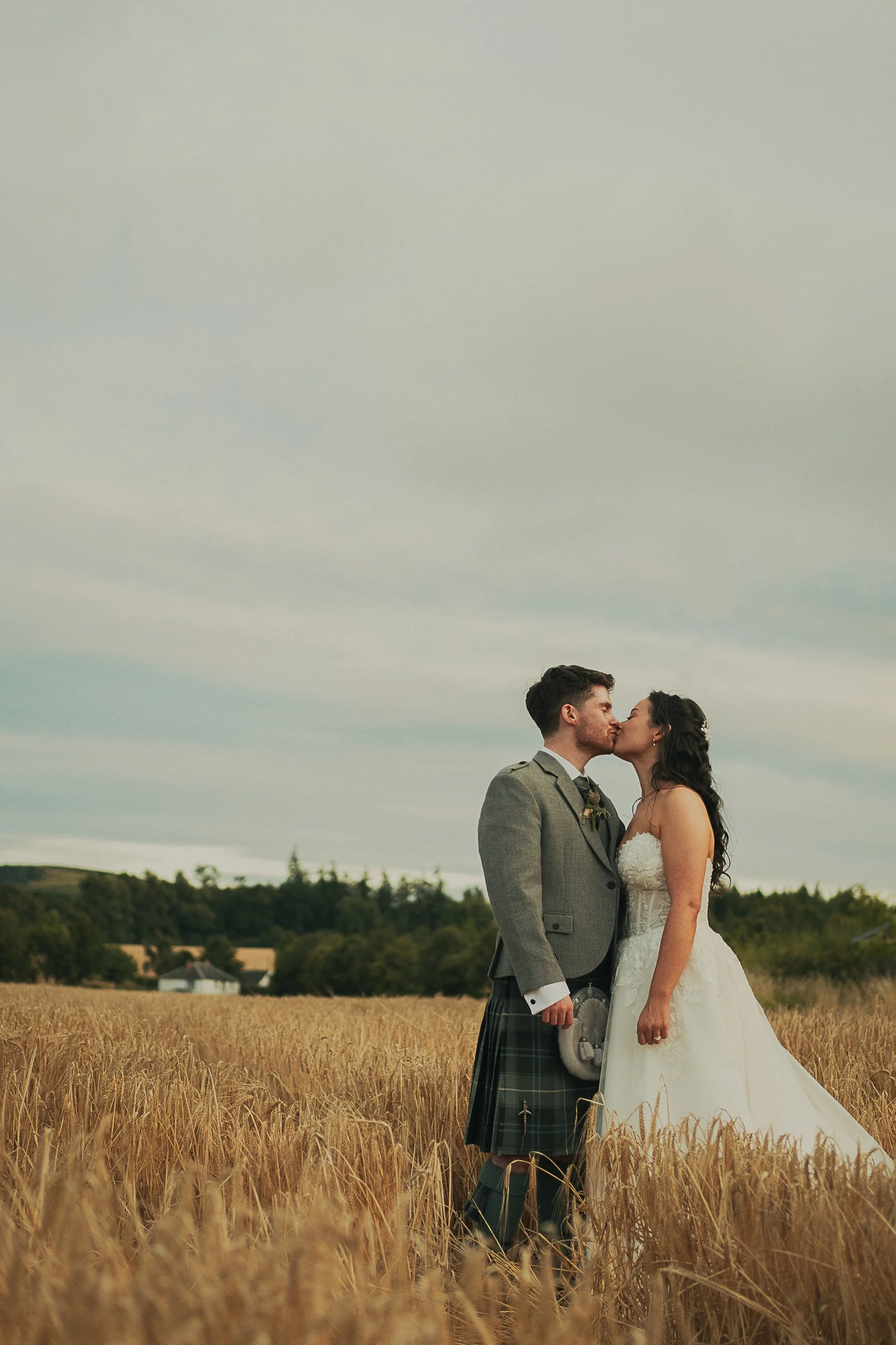 Josie and David sharing a romantic kiss in a barley field during their Perthshire wedding