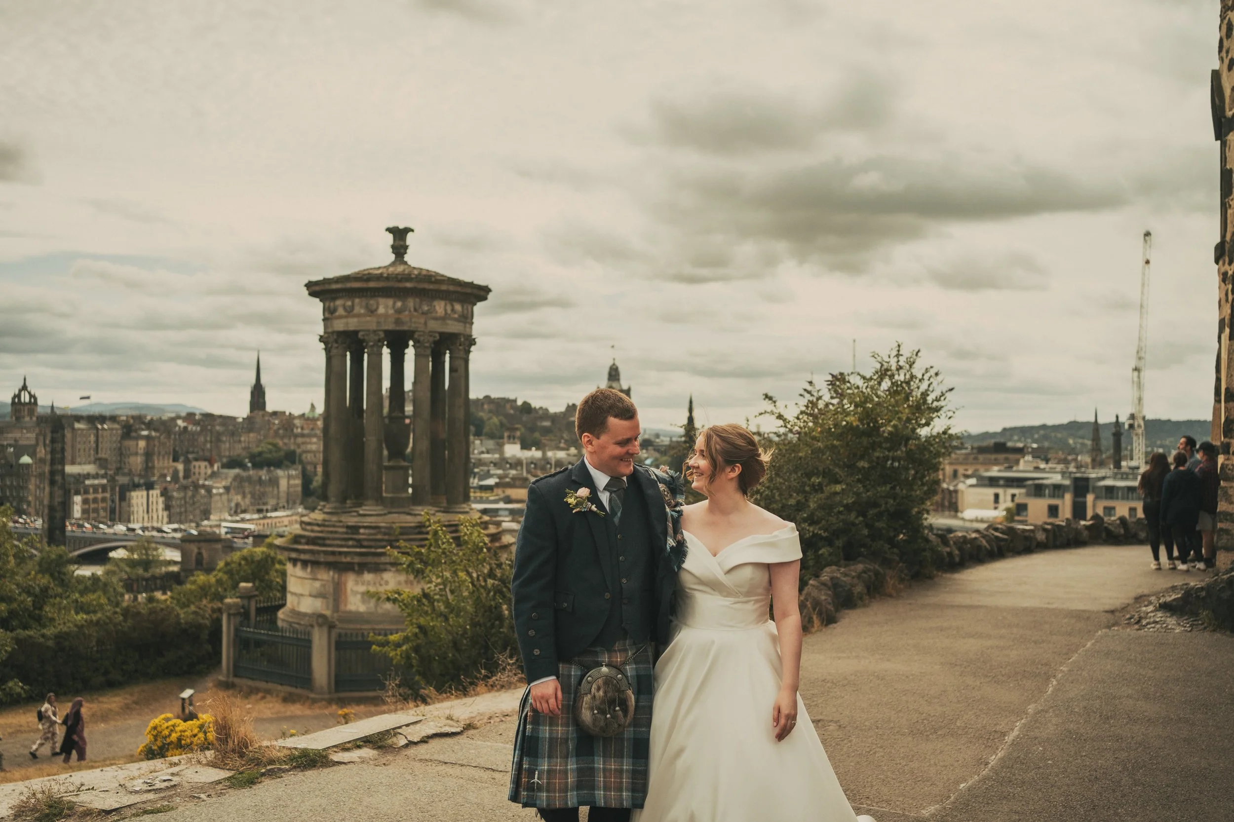 Alexandra and Gavin on Calton Hill with the Dugald Stewart Monument behind them during their Edinburgh wedding