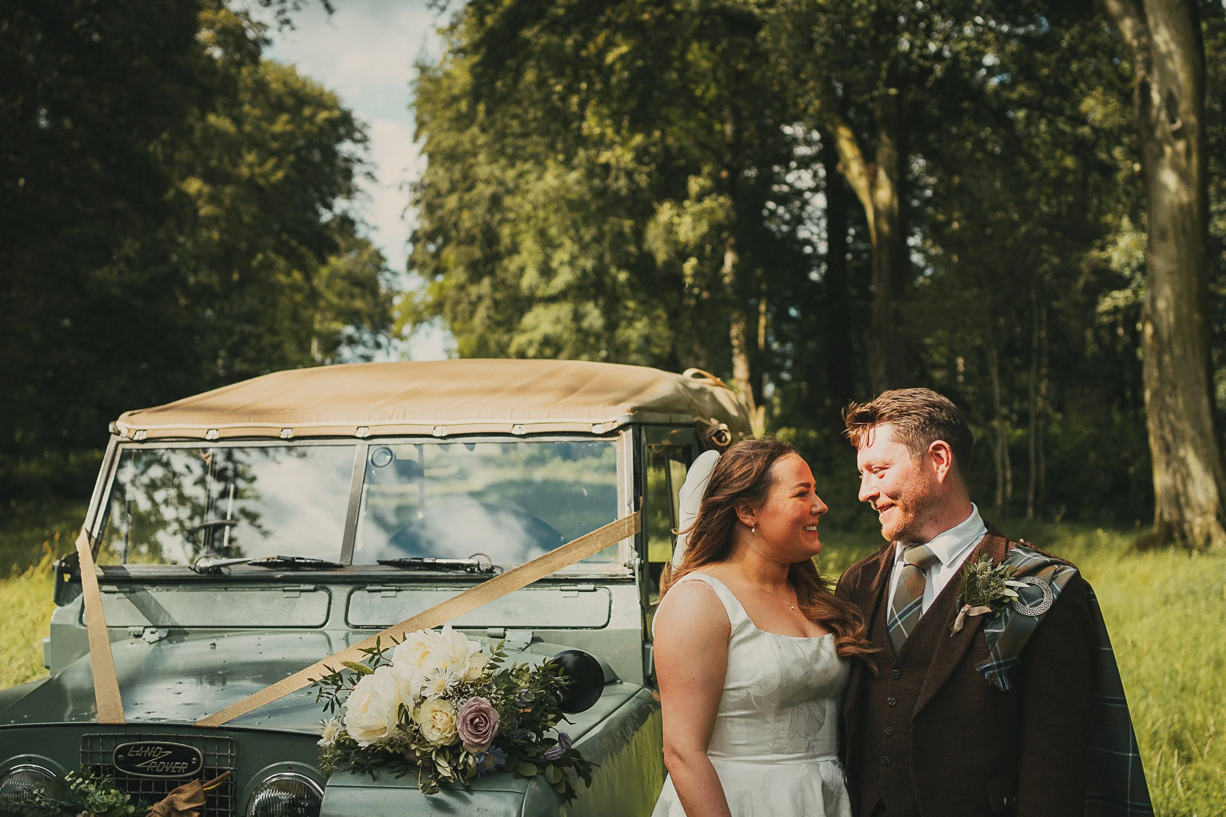 Close-up wedding portrait of Emily and Peter beside a classic Land Rover at Wedderlie House.