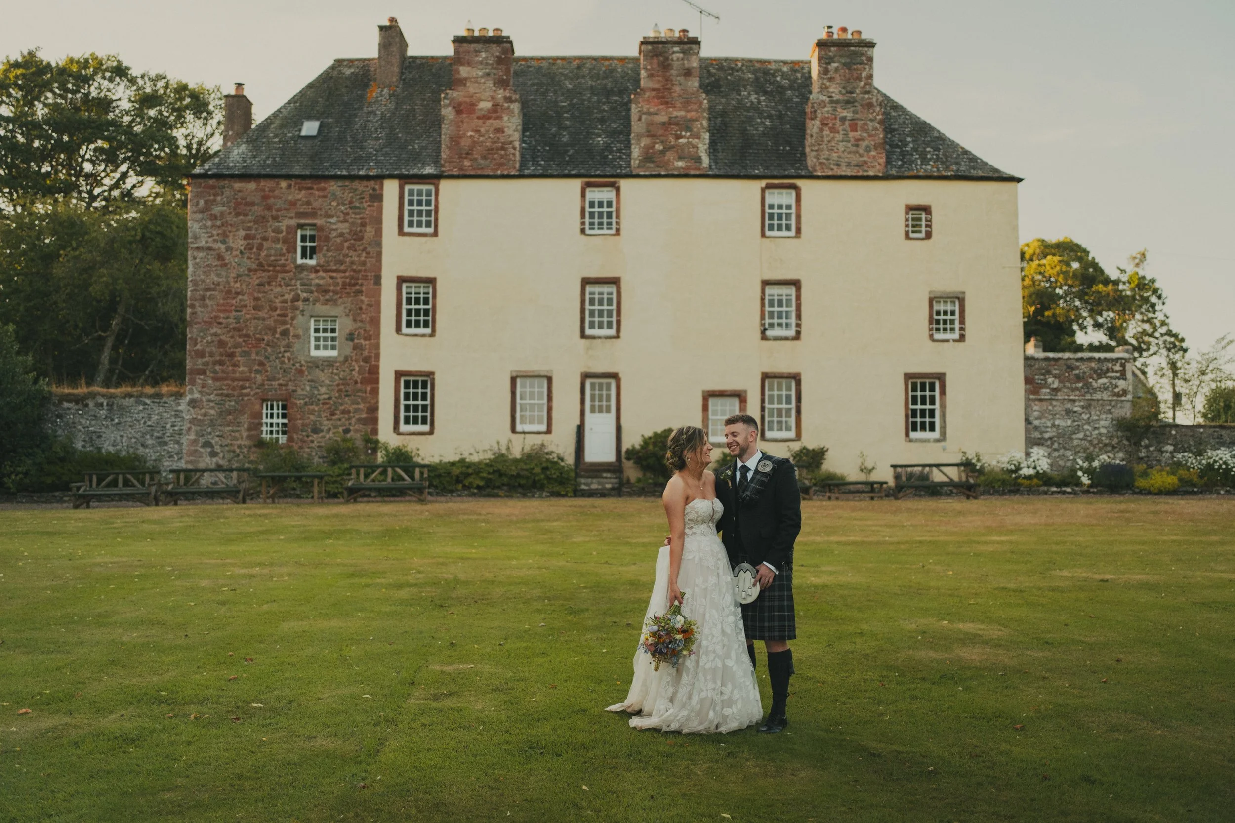 Bryony and Ryan standing together outside Wedderlie House after their Scottish wedding