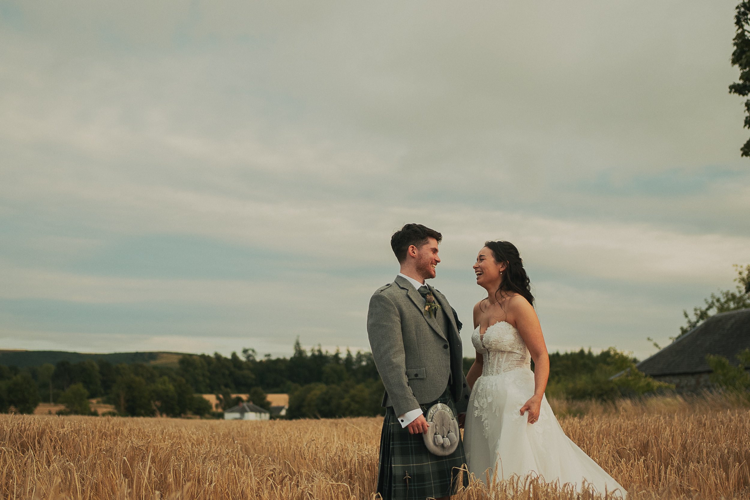 Josie and David embracing in a barley field during their wedding at Rossie on the Earn in Perthshire