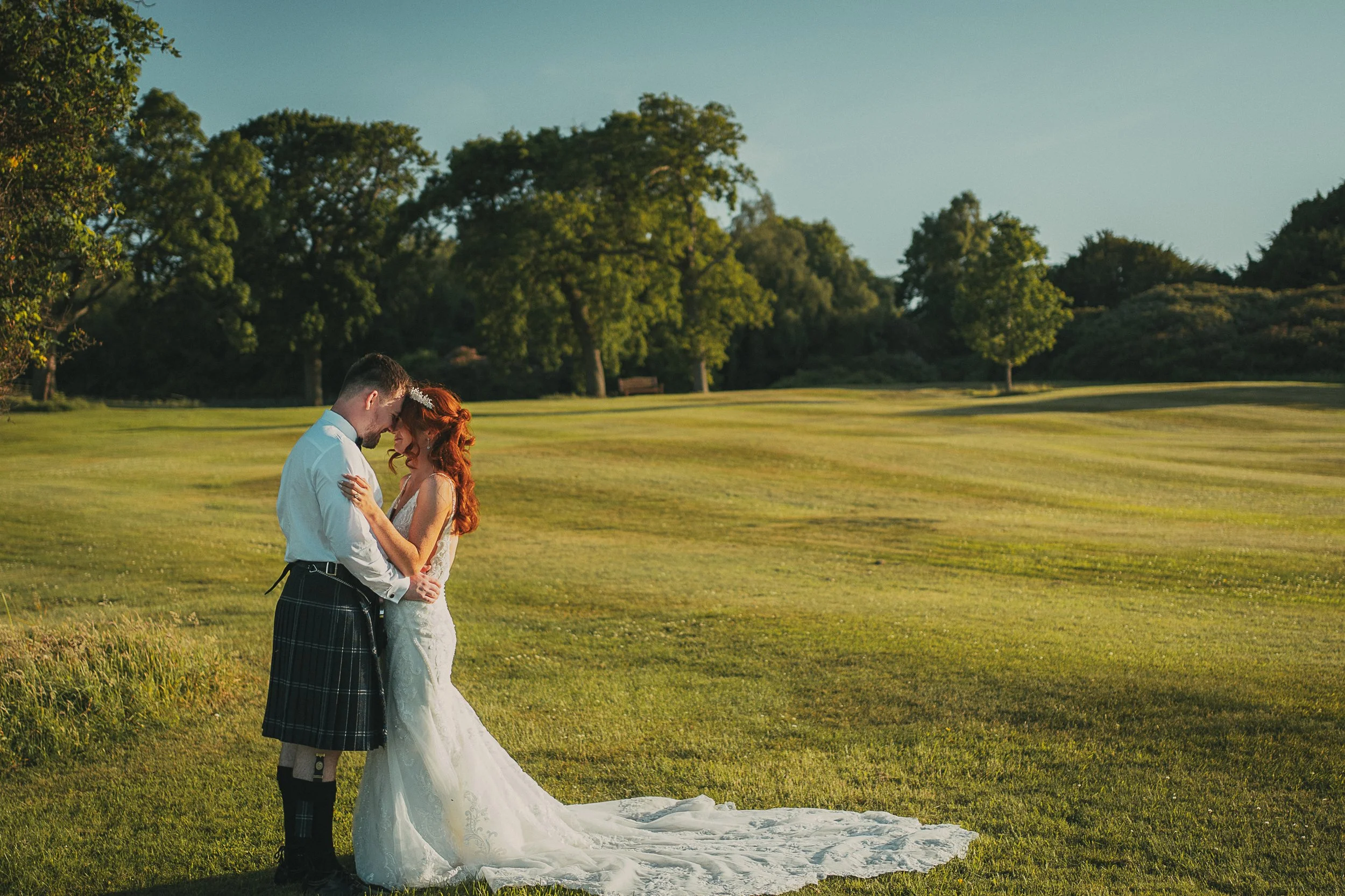 Bride and groom sharing a quiet moment in the gardens at Dundas Castle during their summer wedding in Scotland.