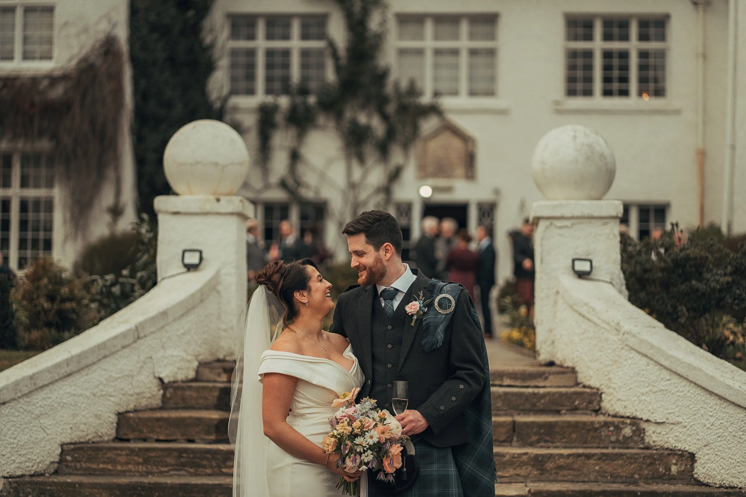 Bride and groom standing on the front steps of Achnagairn during their spring wedding in the Scottish Highlands