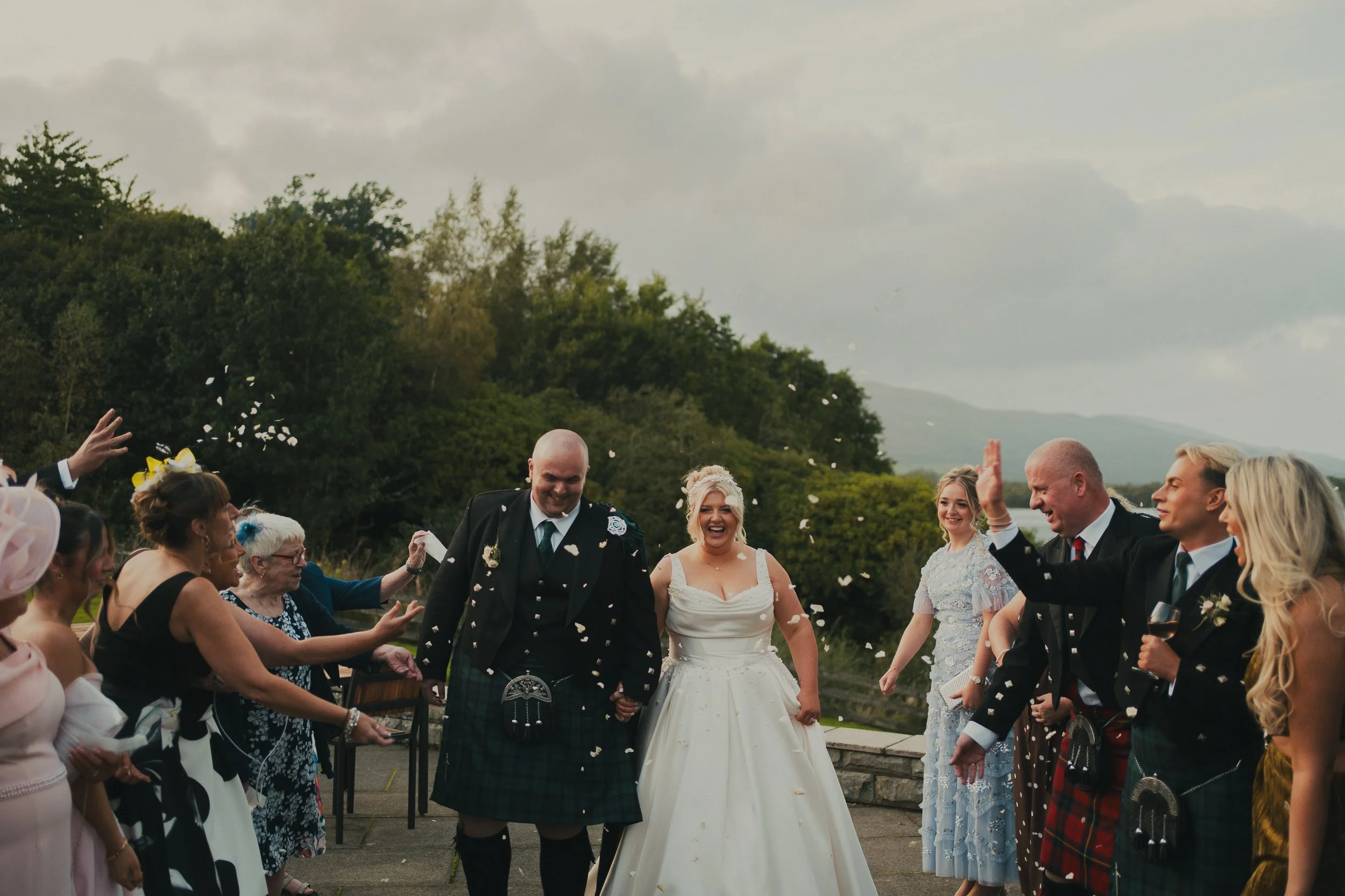 Laura and Nicky walking through confetti after their wedding ceremony at The Cruin Loch Lomond