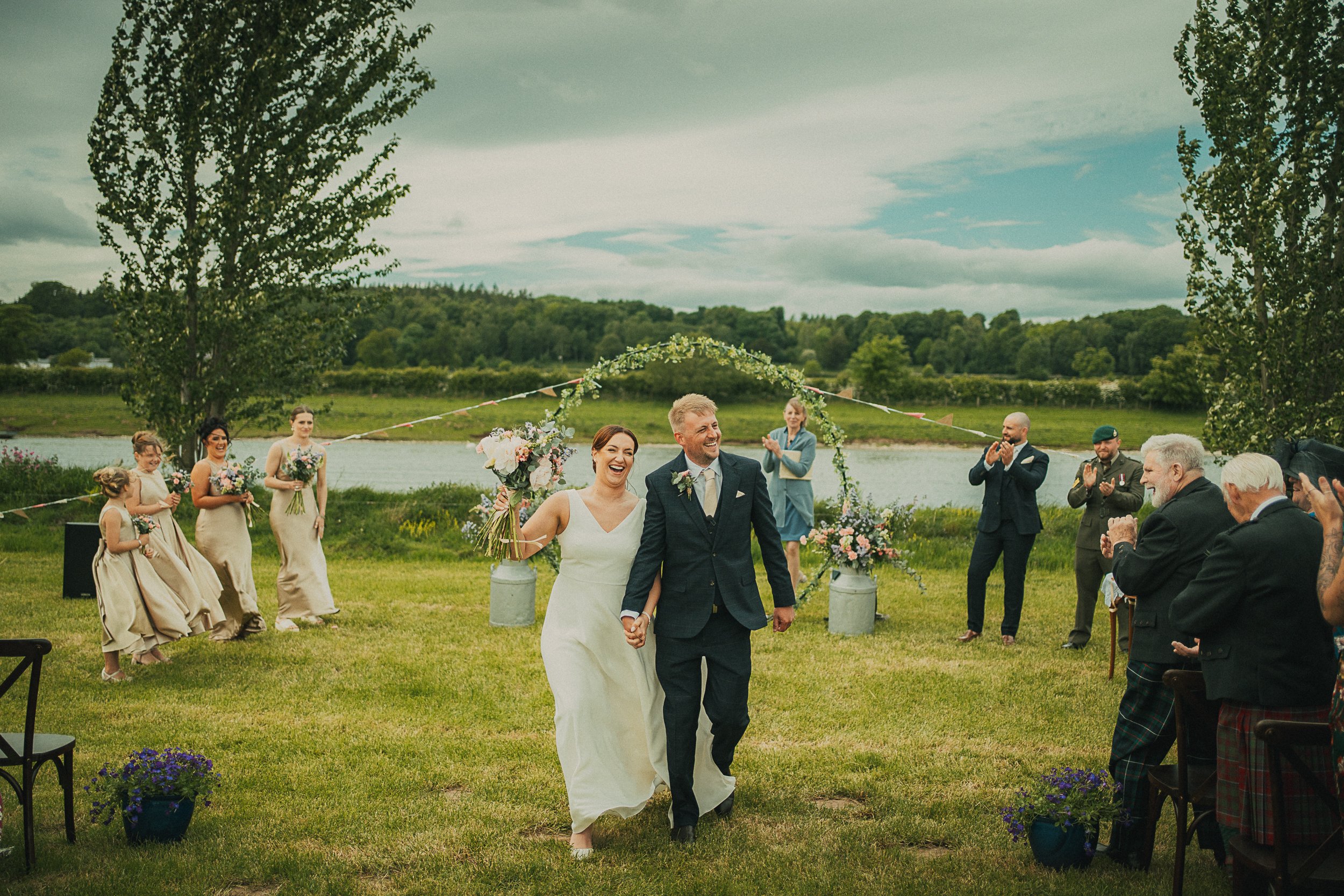 Libby and Nathan walk back up the aisle after their outdoor riverside wedding ceremony beside the River Tweed.