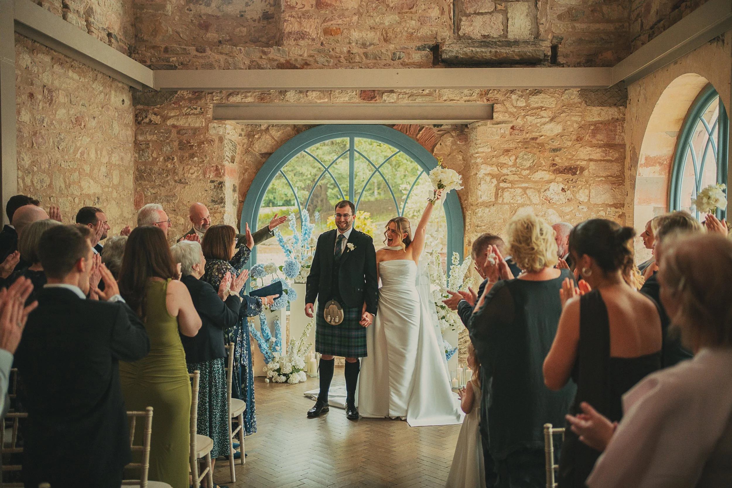 Bride and groom celebrating at the end of their wedding ceremony at Broxmouth Courtyard.
