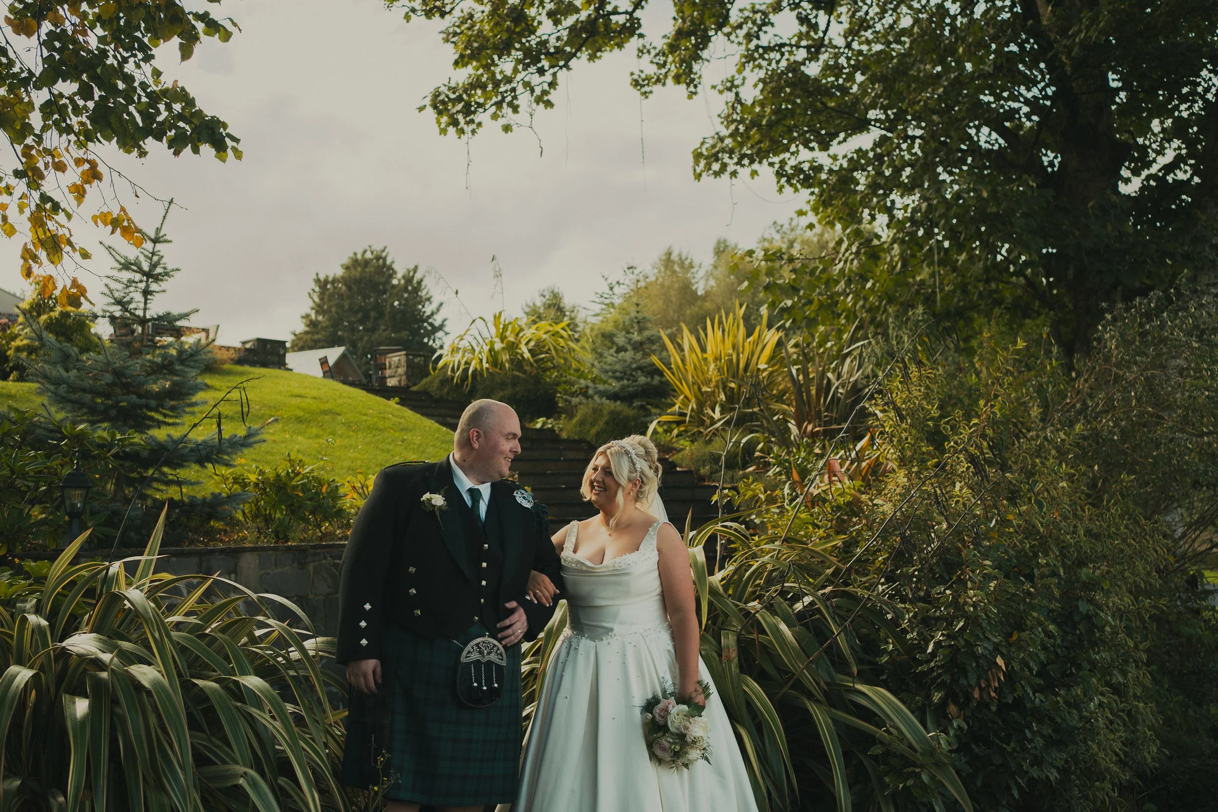 Laura and Nicky looking at each other in the gardens at The Cruin during their Loch Lomond wedding