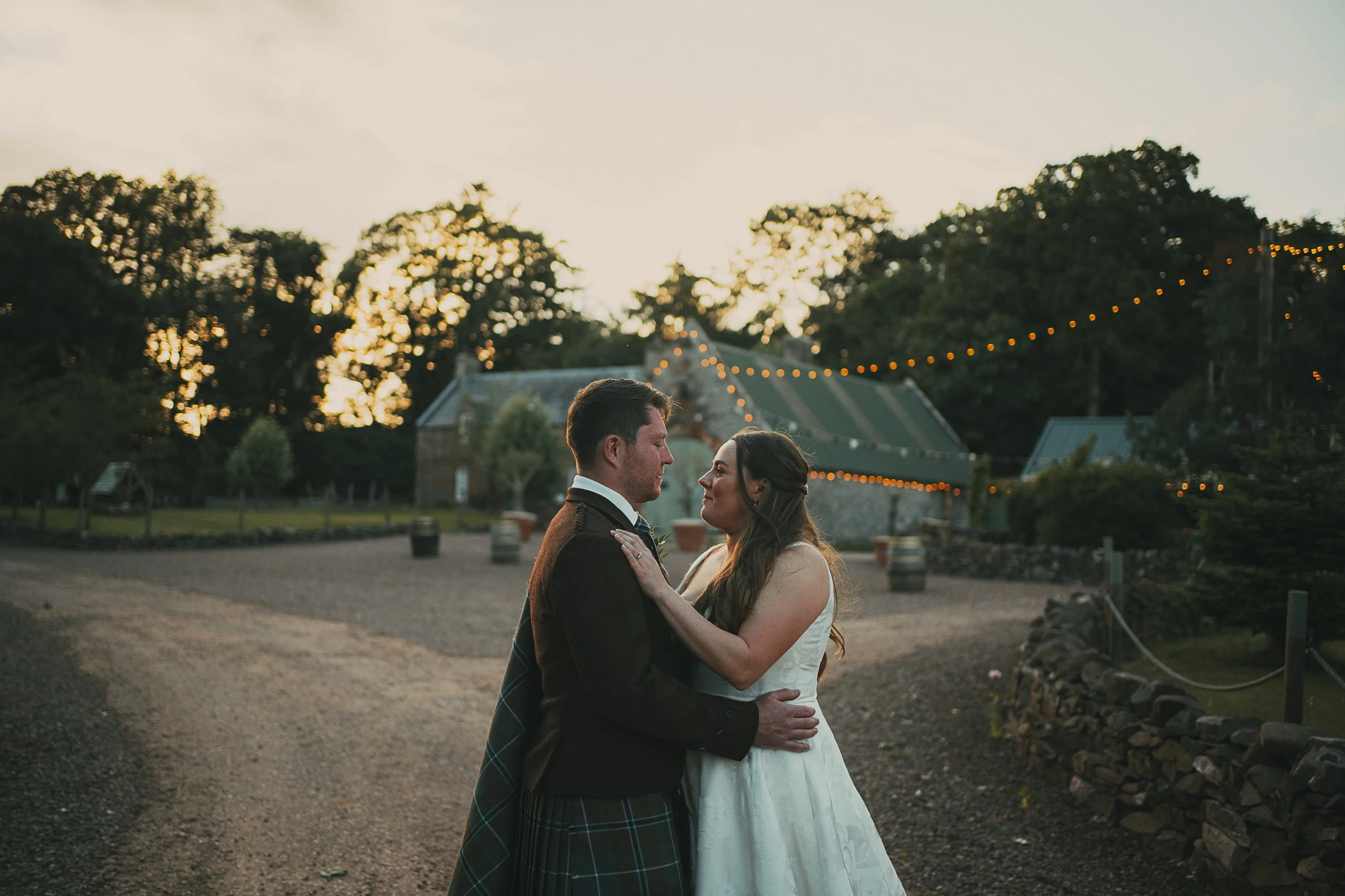 Emily and Peter enjoying evening portraits beneath festoon lights outside the barns at Wedderlie House in the Scottish Borders.