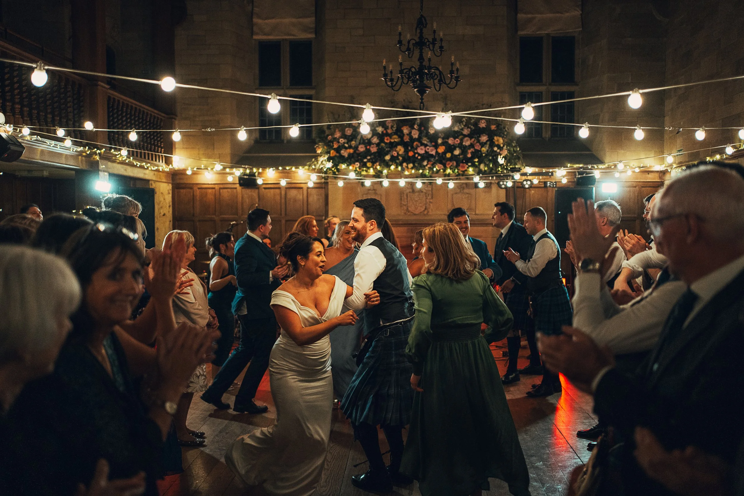 Bride and groom ceilidh dancing with guests during evening reception at Achnagairn