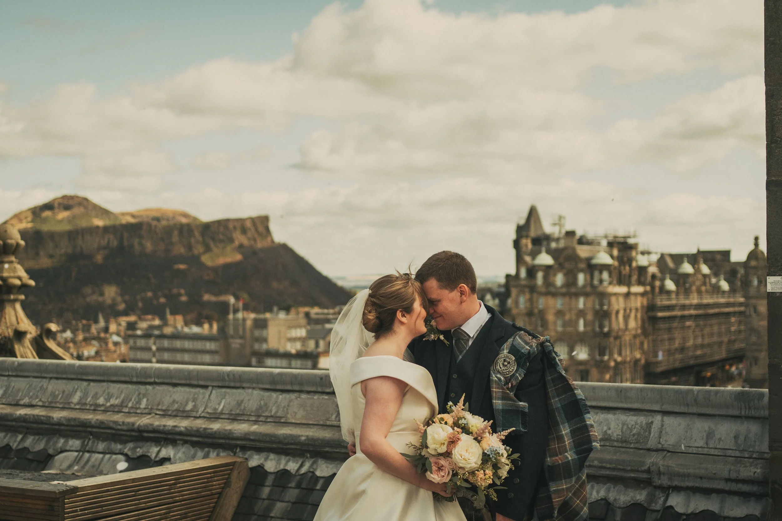 Alexandra and Gavin on The Balmoral Hotel rooftop with Arthur's Seat in the background