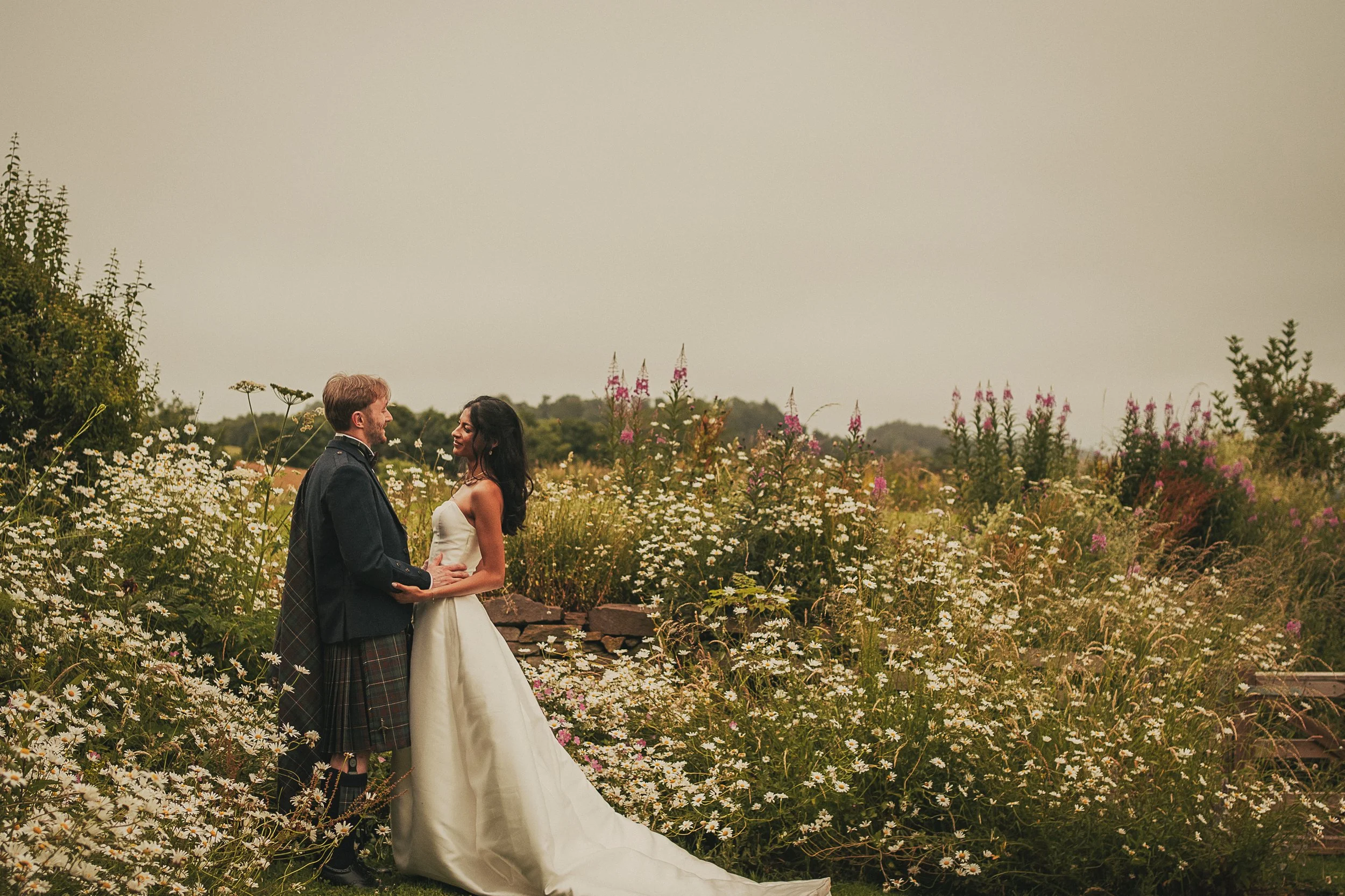 Bride and groom looking at one another in  a wildflower meadow during their Guardswell Farm wedding in Perthshire, Scotland.