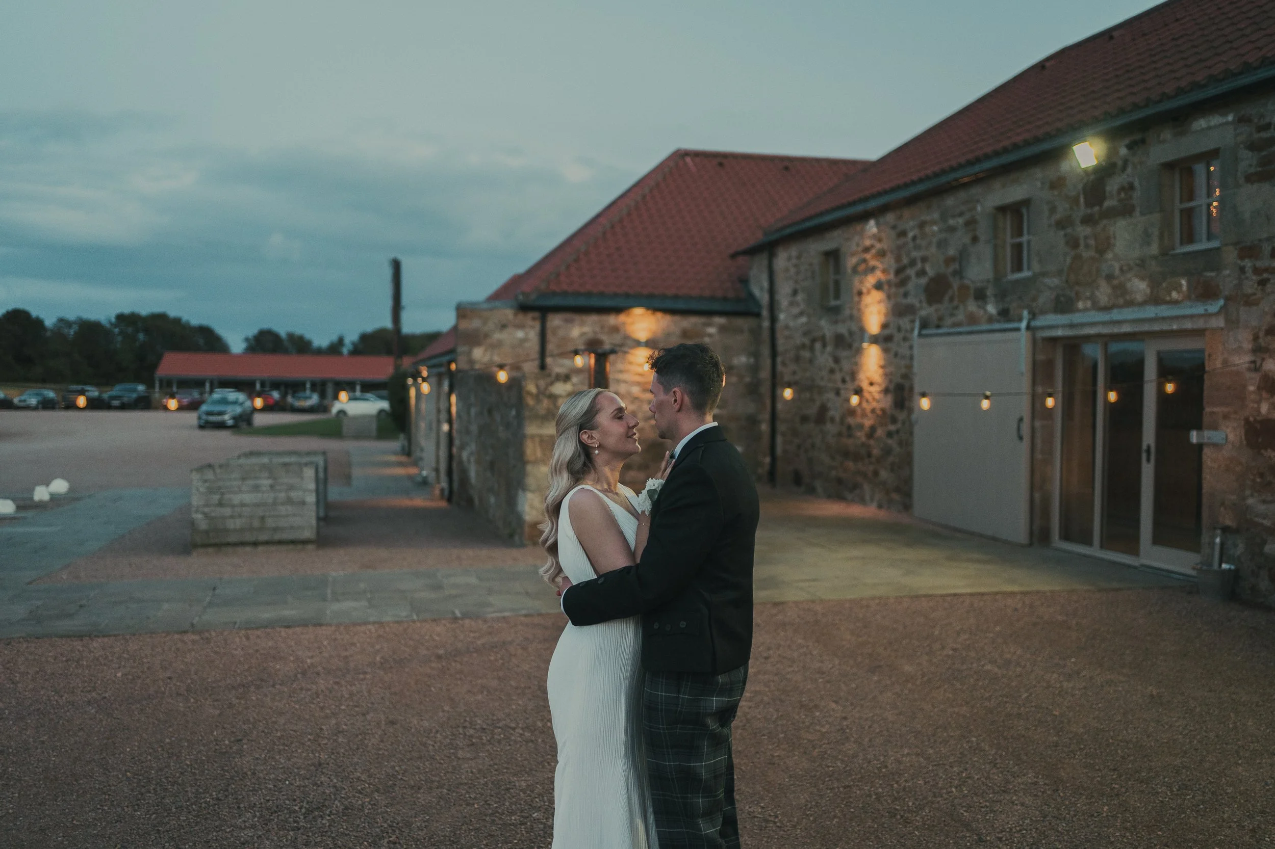 Robyn and Robbie embracing in front of Falside Mill after their wedding ceremony