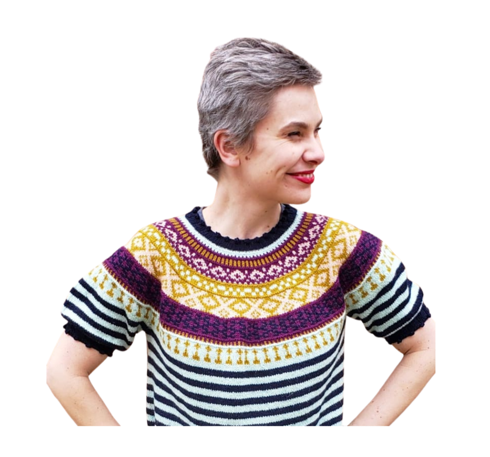 Woman with short gray hair wearing a colorful patterned sweater, smiling and looking to the side, against a plain white background.
