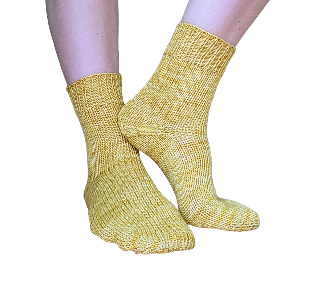 Person wearing yellow knitted socks on feet against white background.