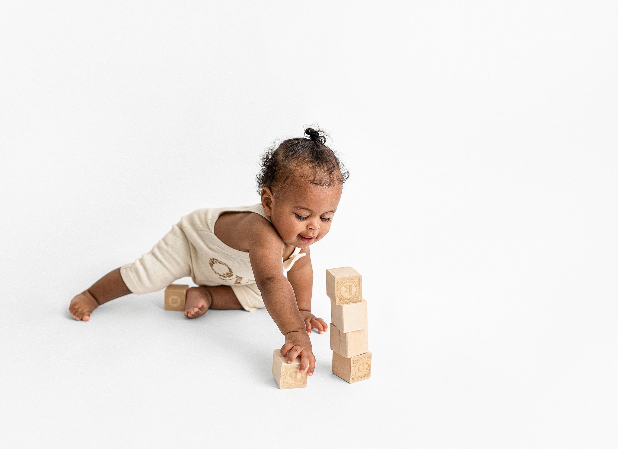 Baby playing with wooden blocks on a white background.