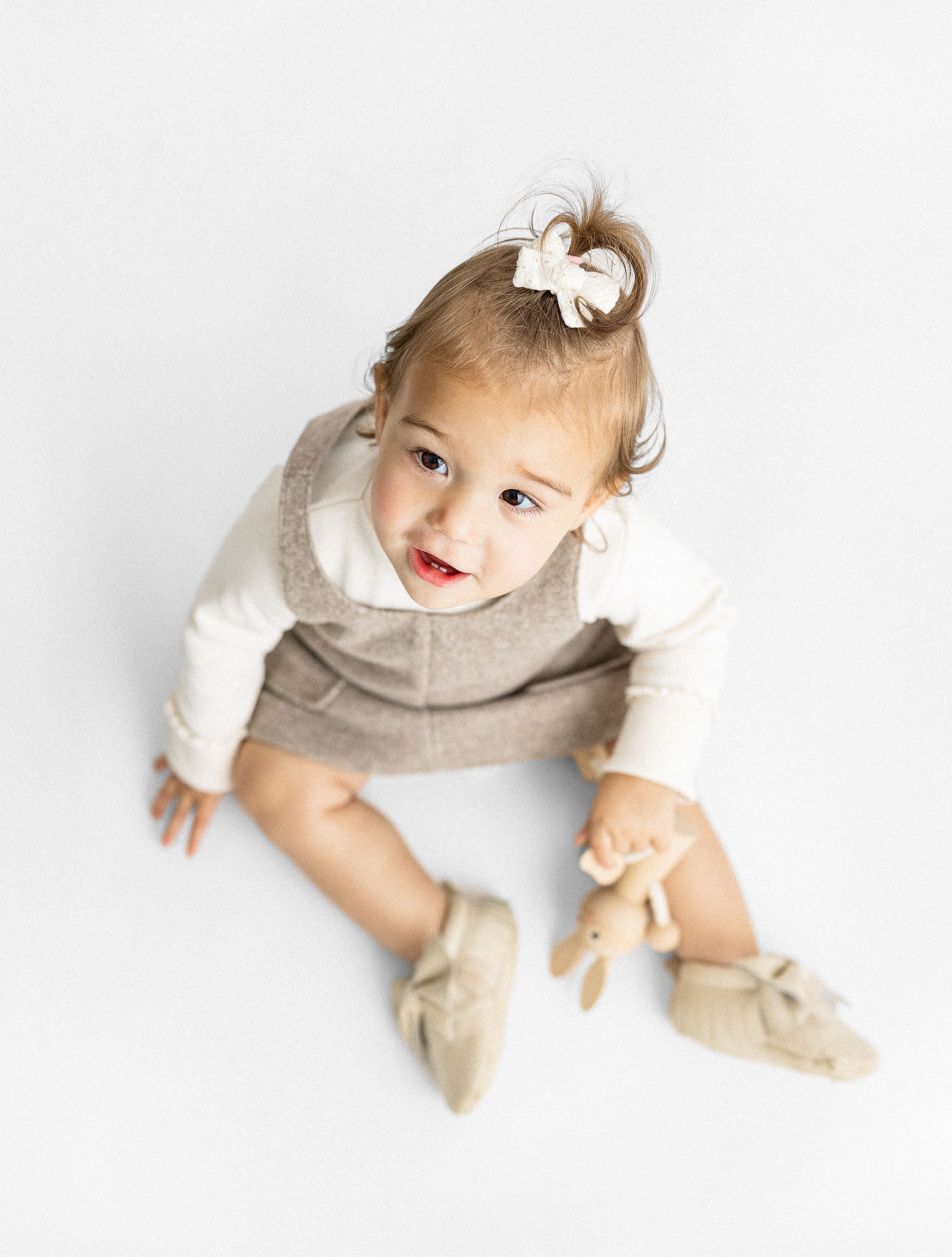 Toddler in brown dress holding stuffed toy