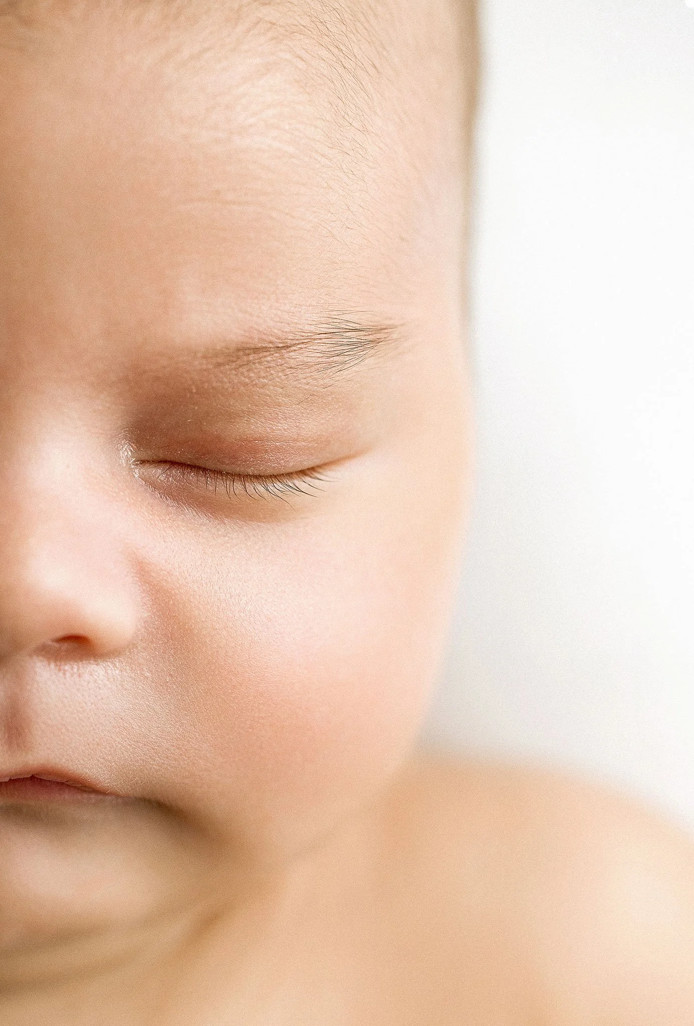 Close-up of a sleeping baby's face with eyes closed and soft skin.