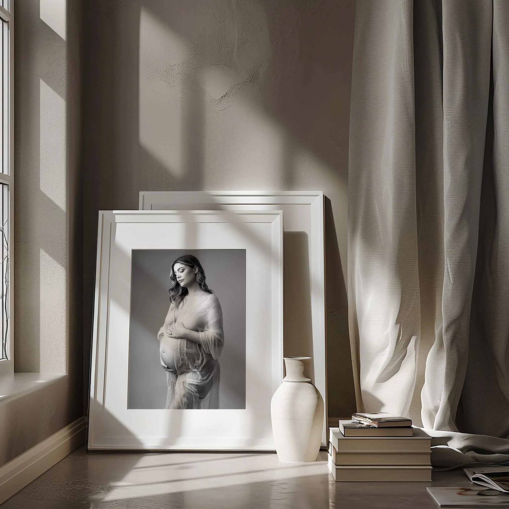 Black and white woman's portrait poster leaning against a wall in a room with a wood floor, beige walls, and curtains. The woman appears to have long wavy hair and is looking down.