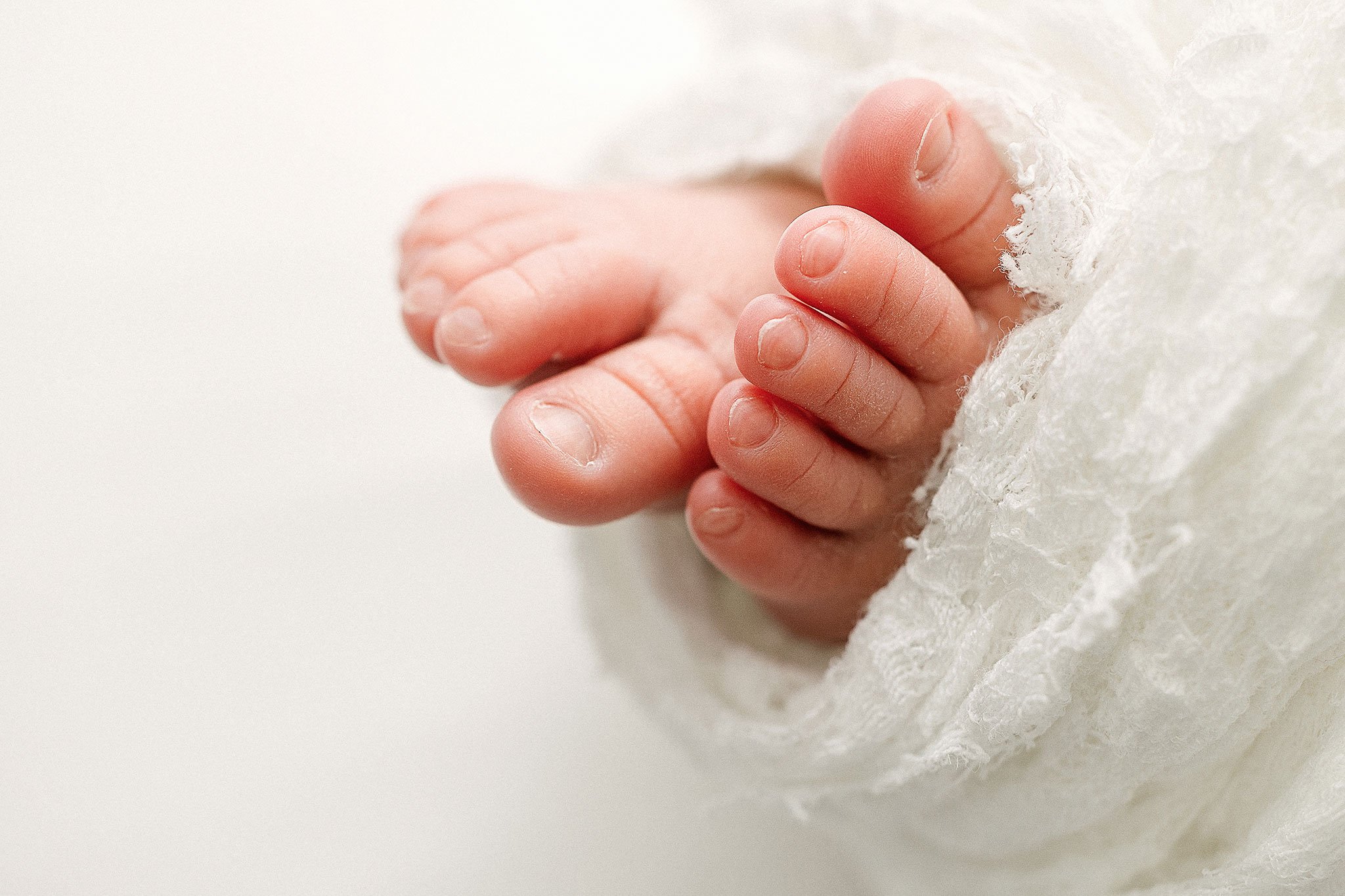 Close-up of baby feet wrapped in a soft white blanket.