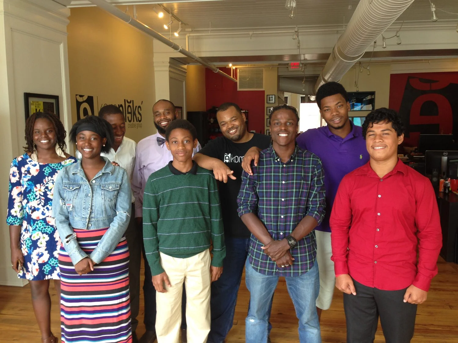 SUMMER CAMP ASSISTANT DIRECTOR ISAIAH SIMMS (BOW TIE), COUNSELOR FRANK SMITH (BLUE PLAID), AND CIT DEMICHEAL BURTON (PURPLE) WITH YOUTH DURING A SMALL BUSINESS FIELD TRIP AT KOMPLEKS CREATIVE DESIGN FIRM